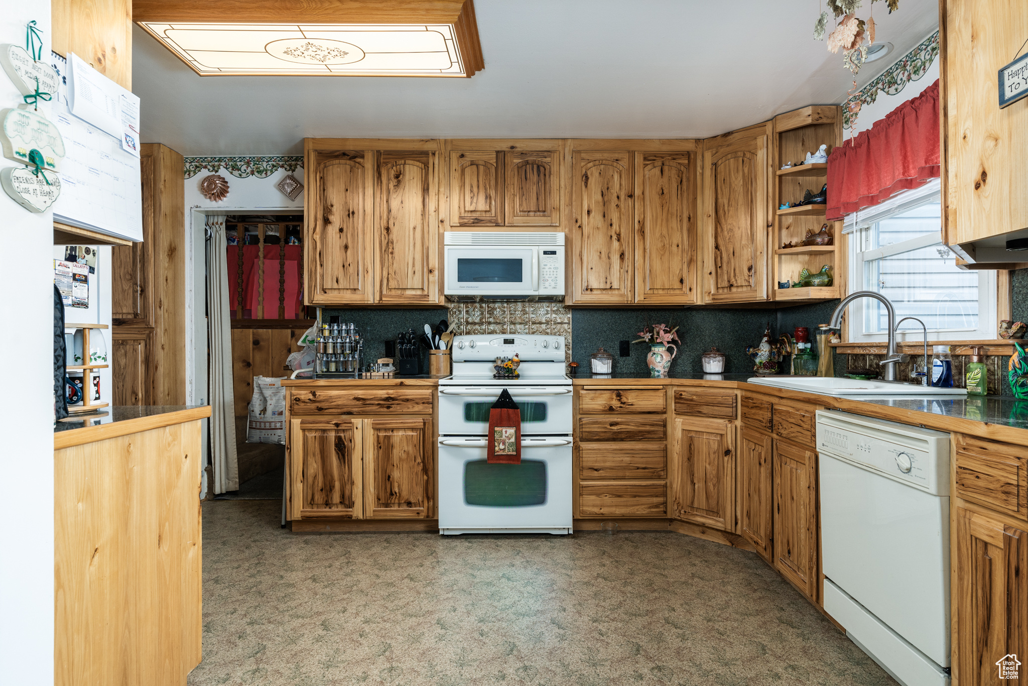Kitchen with white appliances, light countertops, a sink, and brown cabinetry