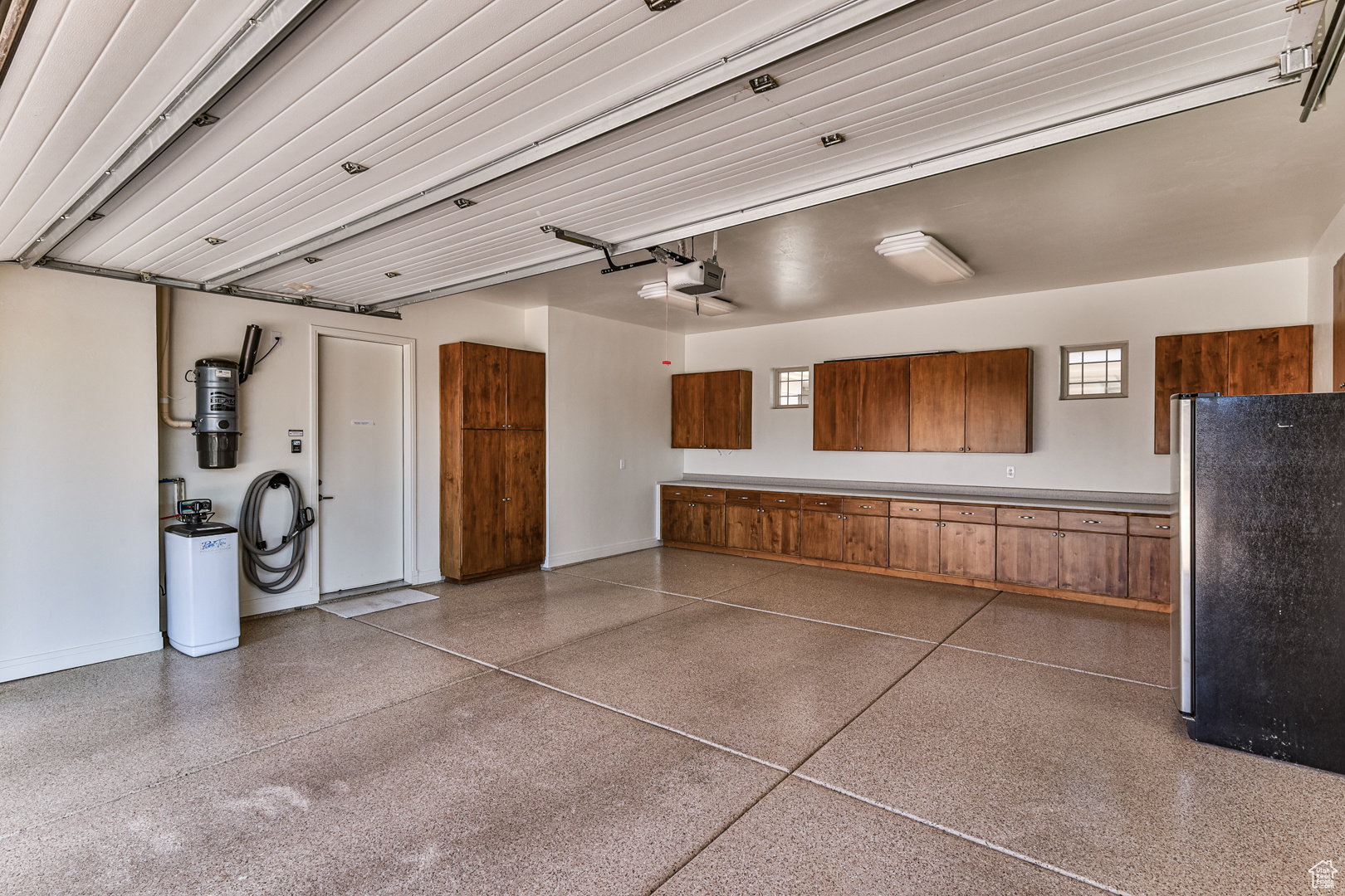 Garage featuring a garage door opener and stainless steel fridge