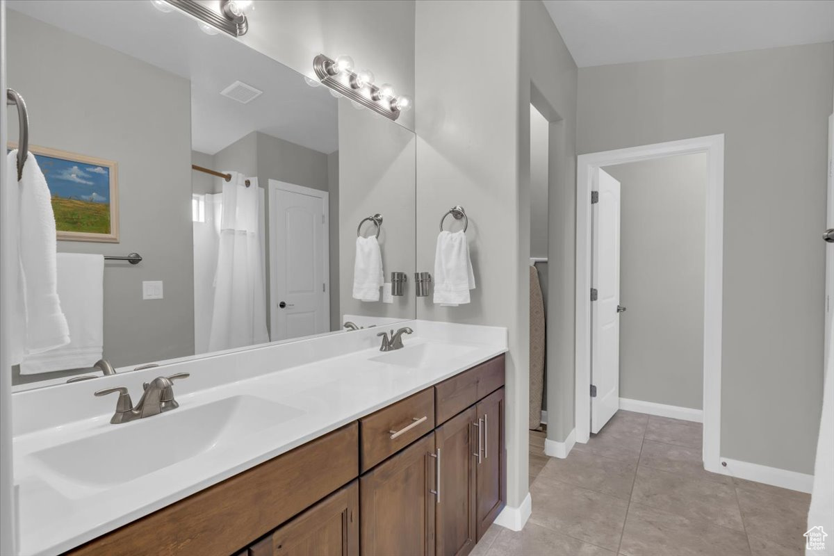 Full bathroom featuring tile patterned floors, a sink, baseboards, and double vanity