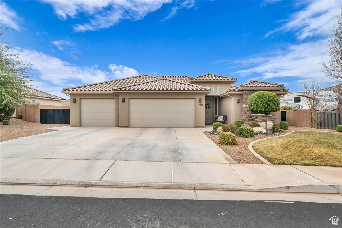 Mediterranean / spanish-style home with driveway, an attached garage, a tiled roof, and stucco siding
