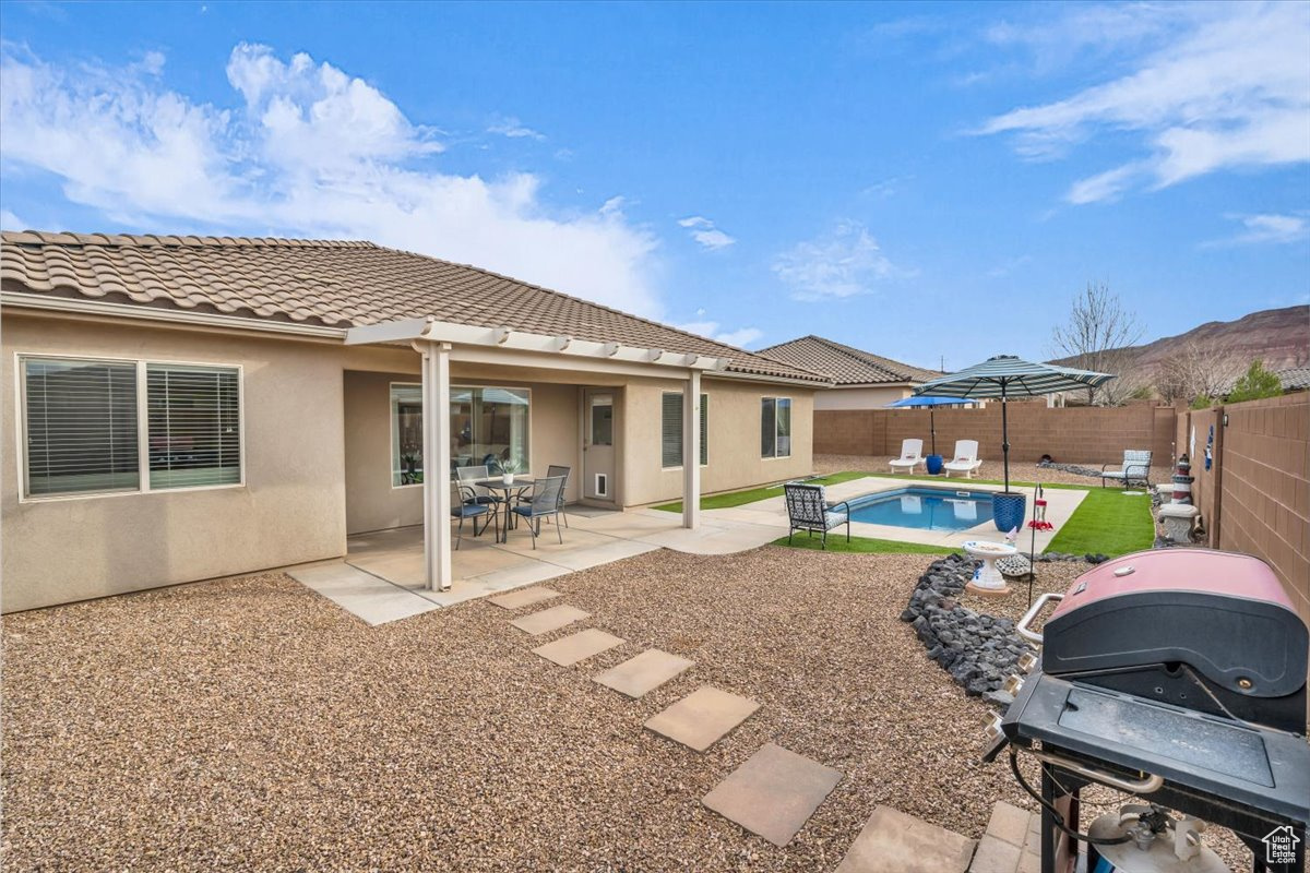 Back of house with a fenced in pool, a patio, stucco siding, a fenced backyard, and a tiled roof