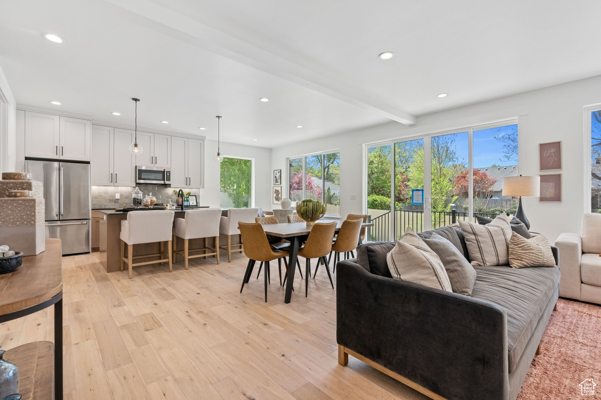 Living area with light wood-style floors, beam ceiling, and recessed lighting