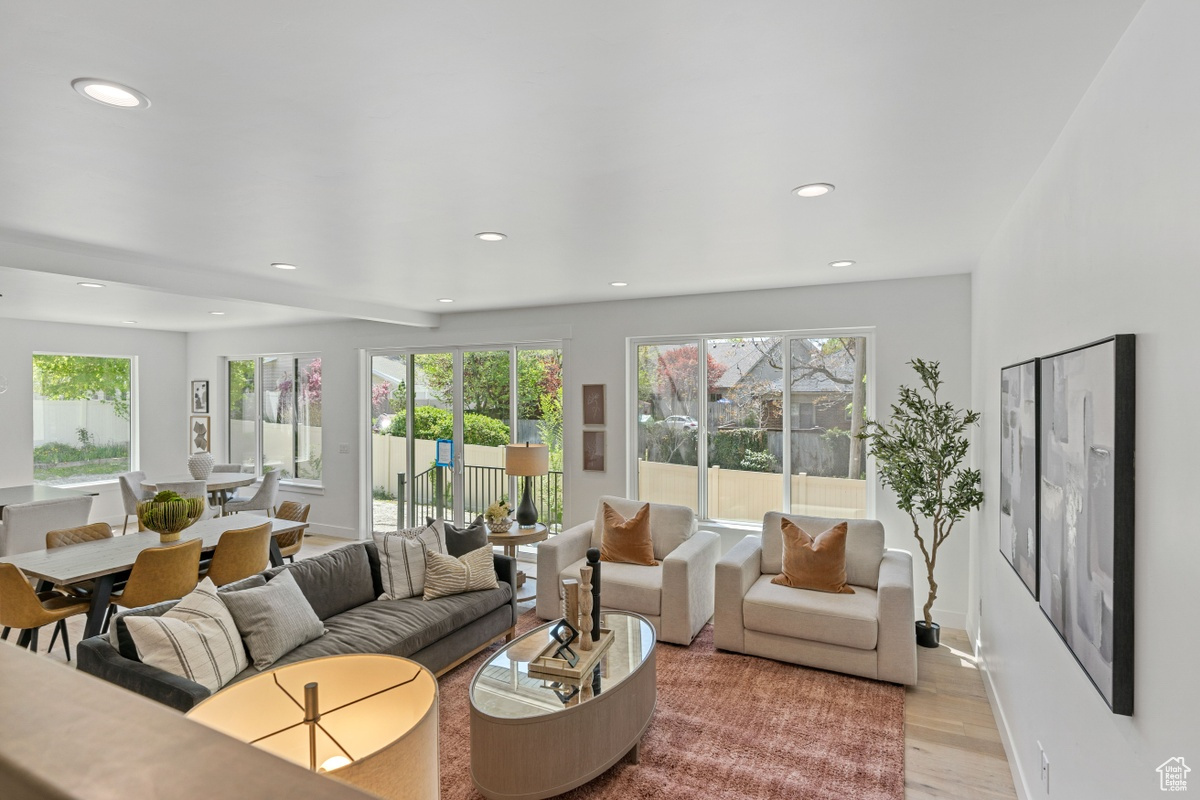 Living room with plenty of natural light, light wood-style flooring, baseboards, and recessed lighting
