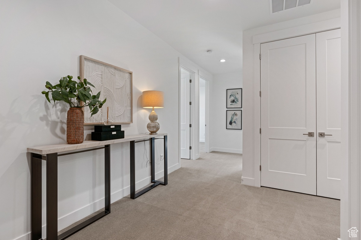 Hall with recessed lighting, baseboards, visible vents, and light colored carpet