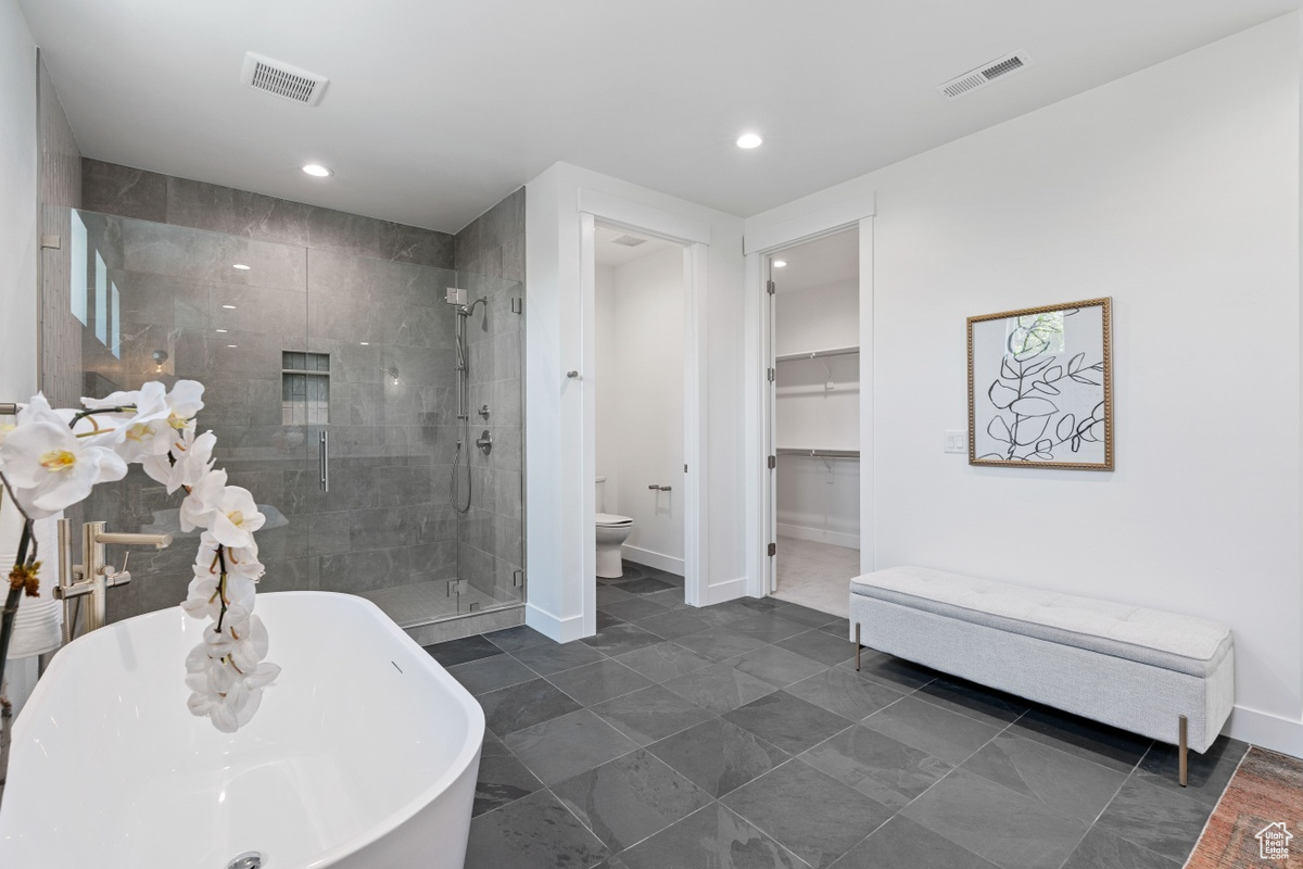 Full bath featuring toilet, a soaking tub, a shower stall, and visible vents