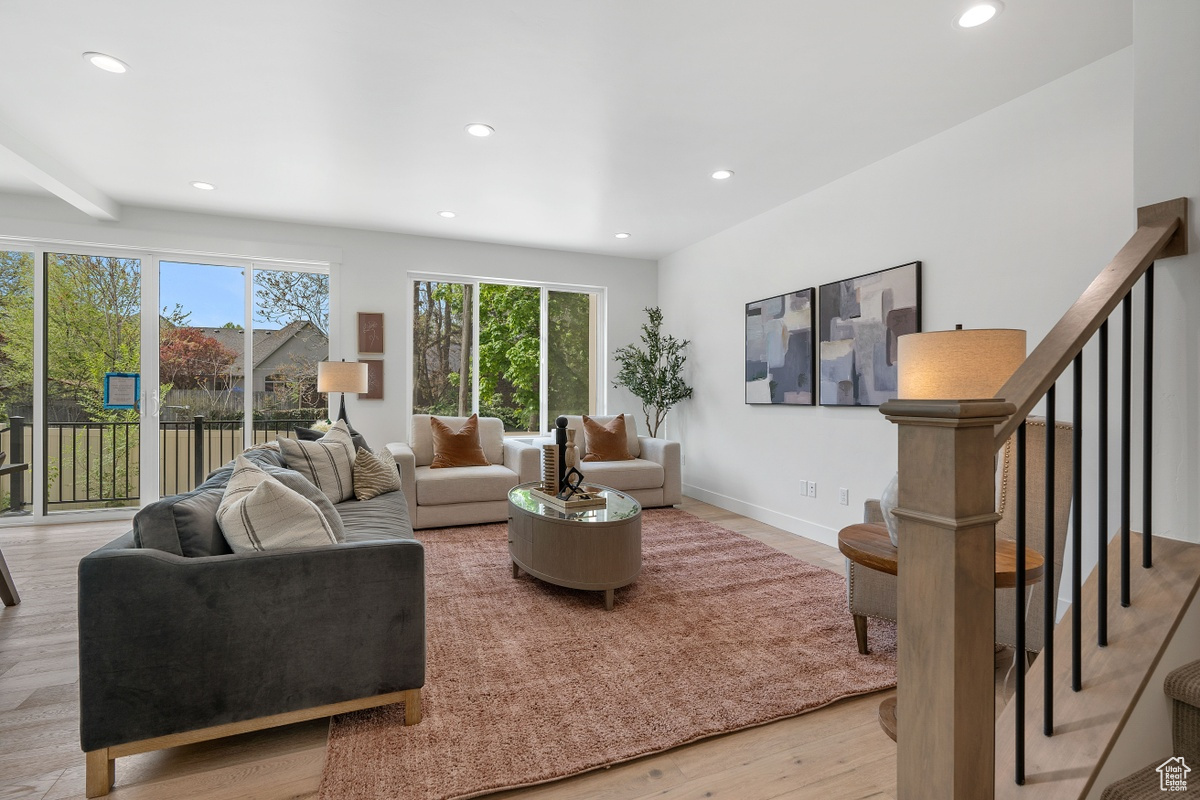 Living room featuring recessed lighting, light wood-style flooring, baseboards, and stairs