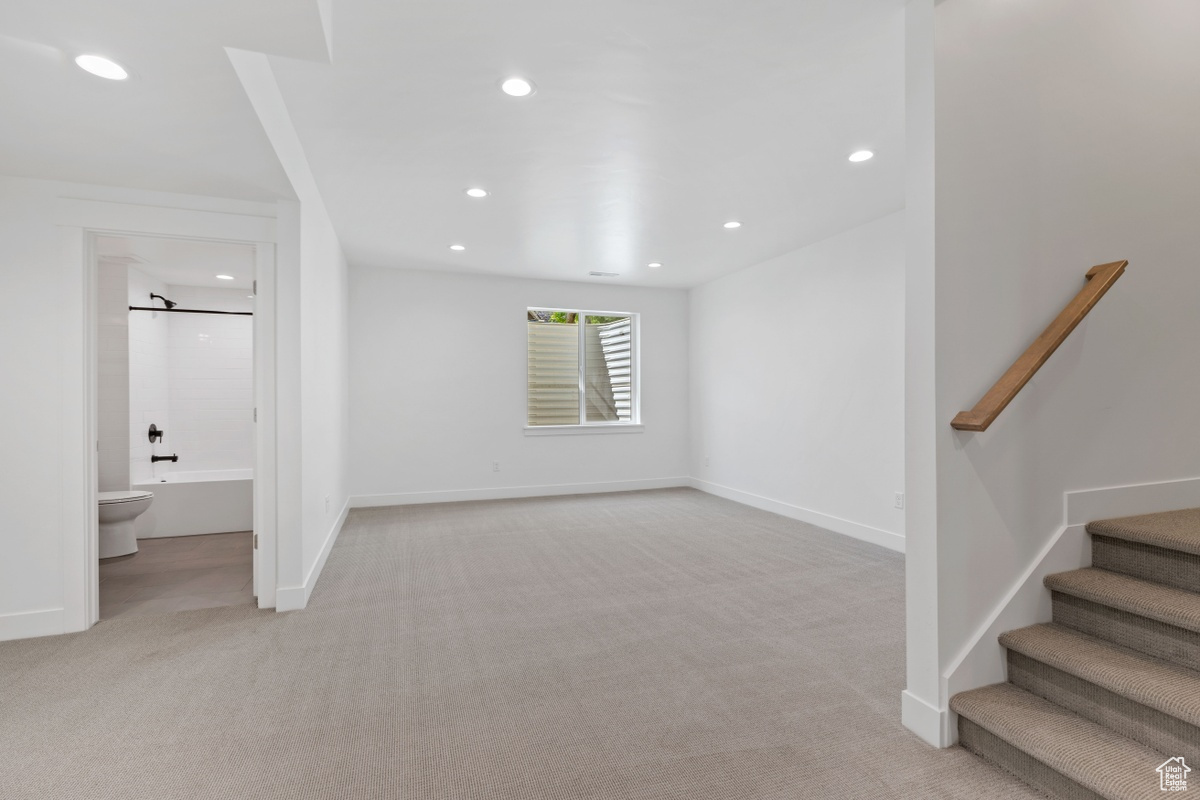 Interior space with baseboards, stairway, recessed lighting, and light colored carpet