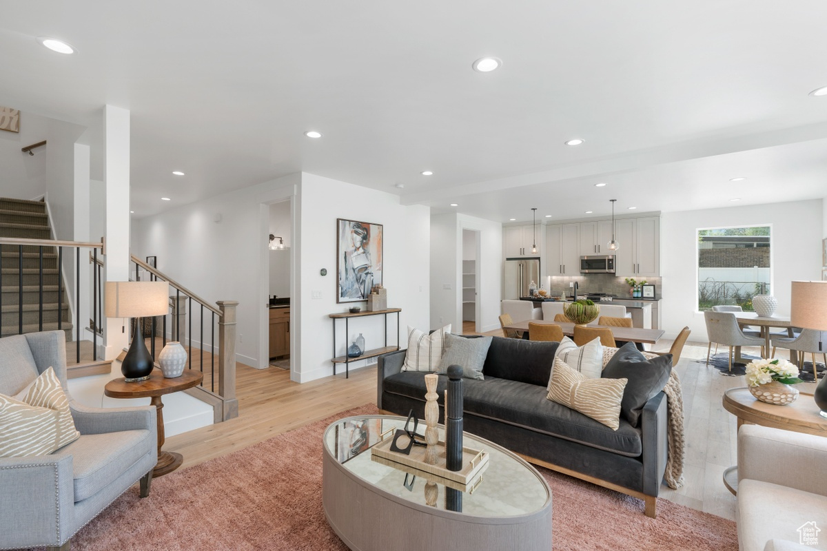 Living room featuring recessed lighting, baseboards, stairway, and light wood finished floors