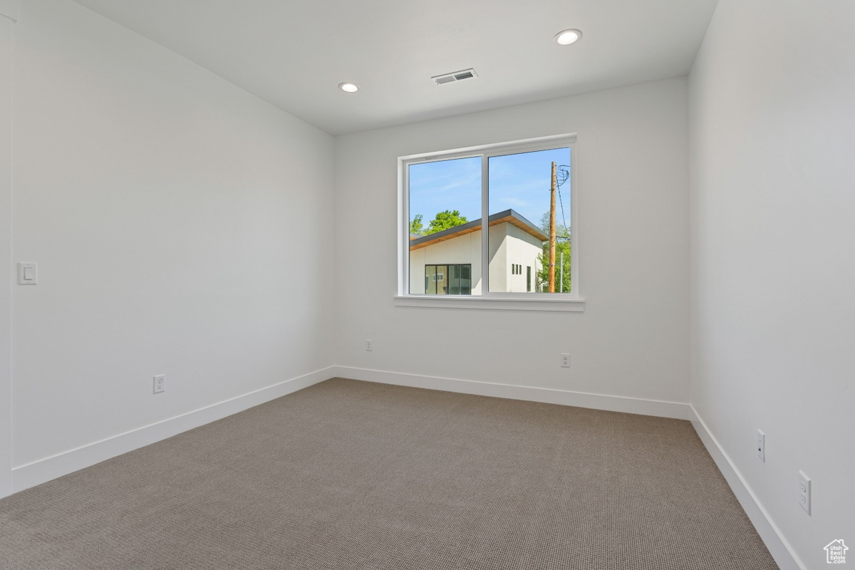 Carpeted empty room with recessed lighting, visible vents, and baseboards