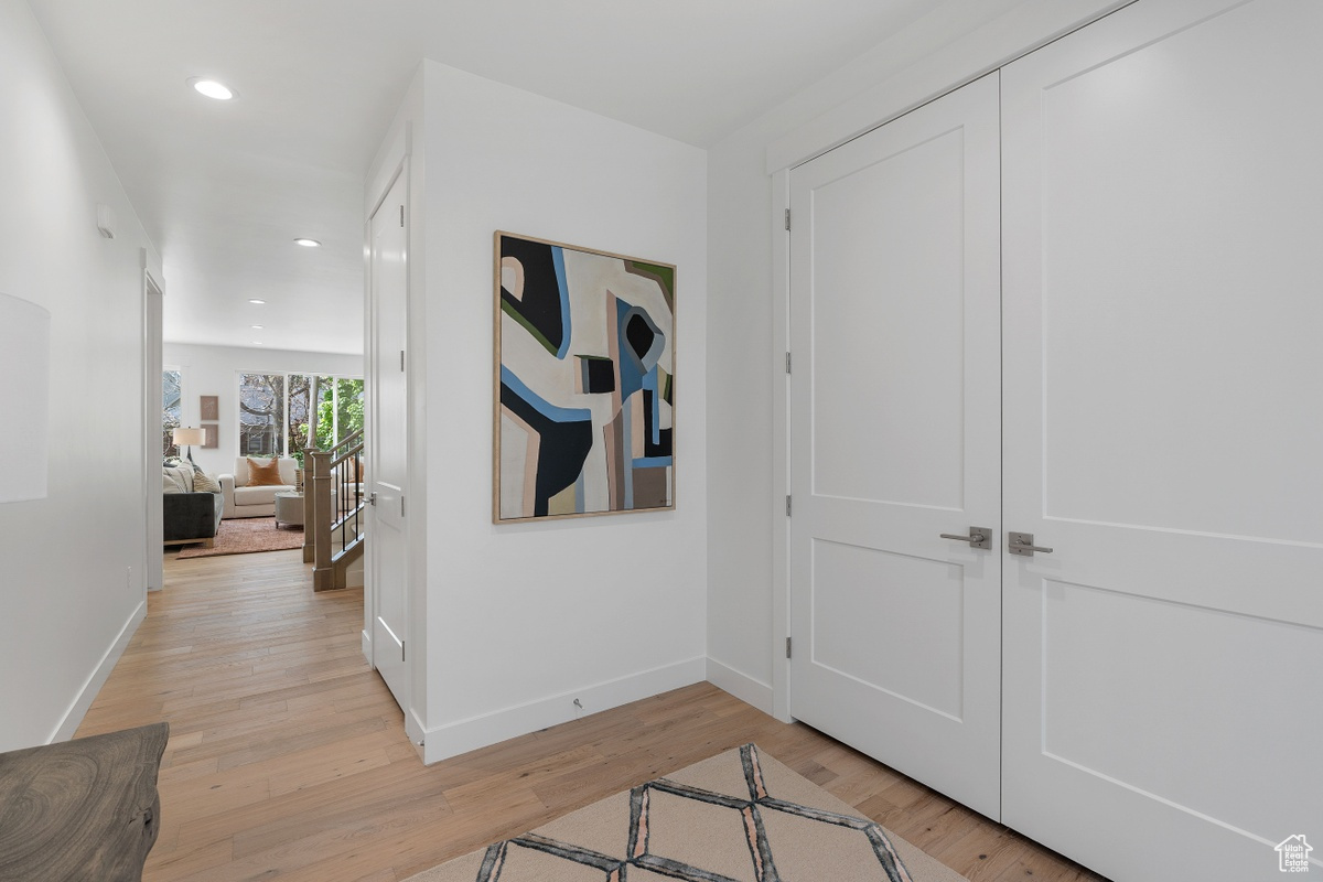 Corridor featuring baseboards, light wood-type flooring, and recessed lighting
