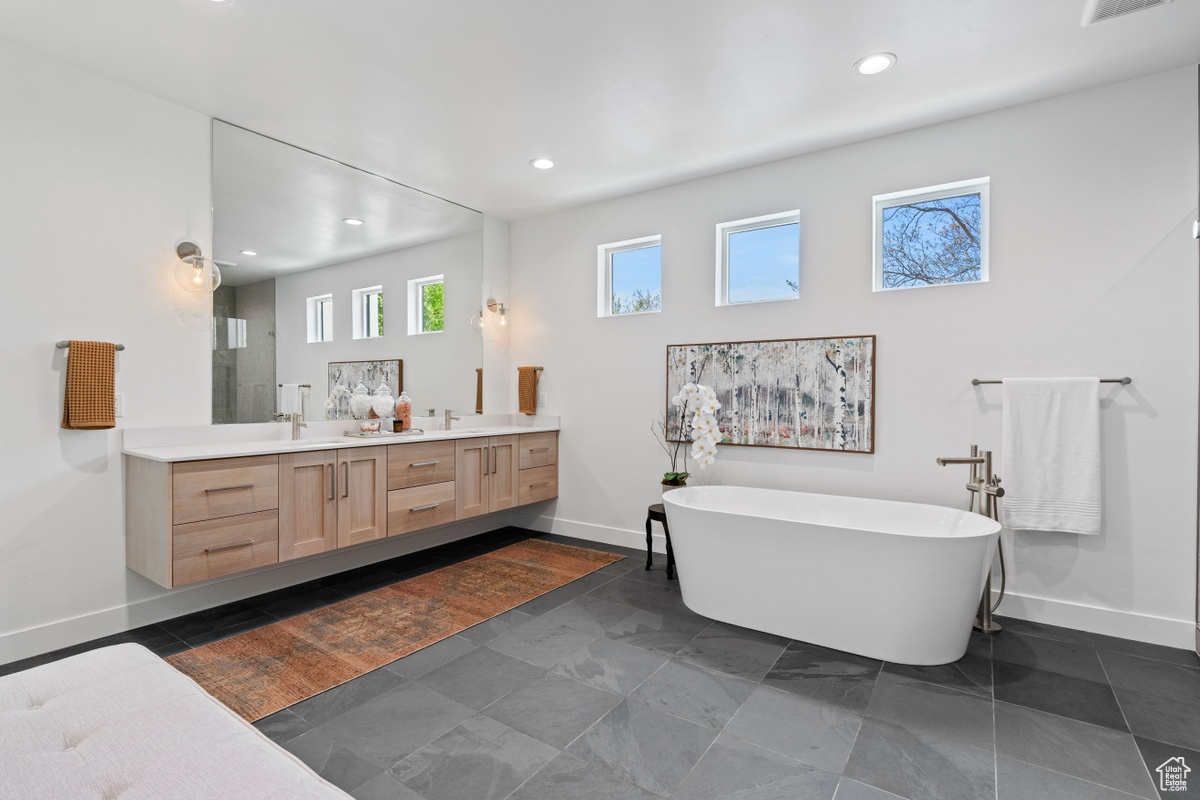 Full bath featuring double vanity, visible vents, baseboards, a soaking tub, and recessed lighting