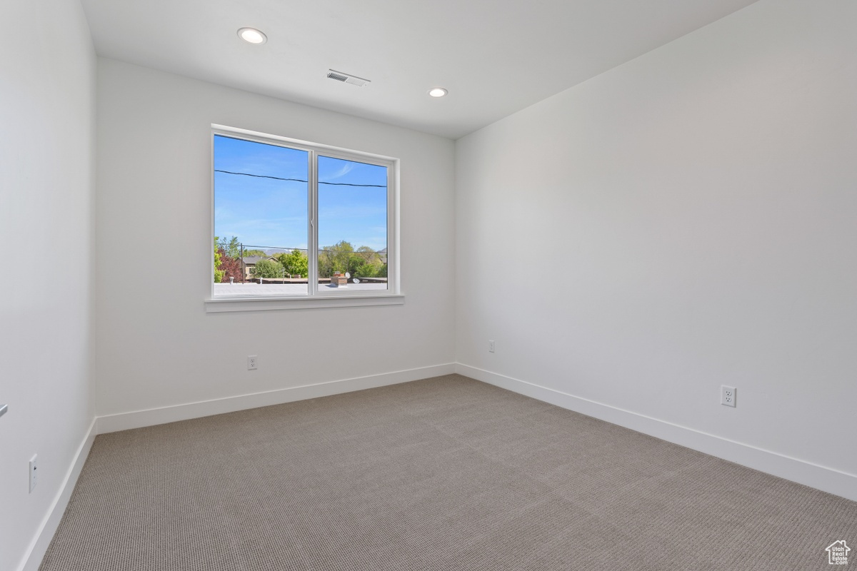 Spare room with recessed lighting, light colored carpet, visible vents, and baseboards