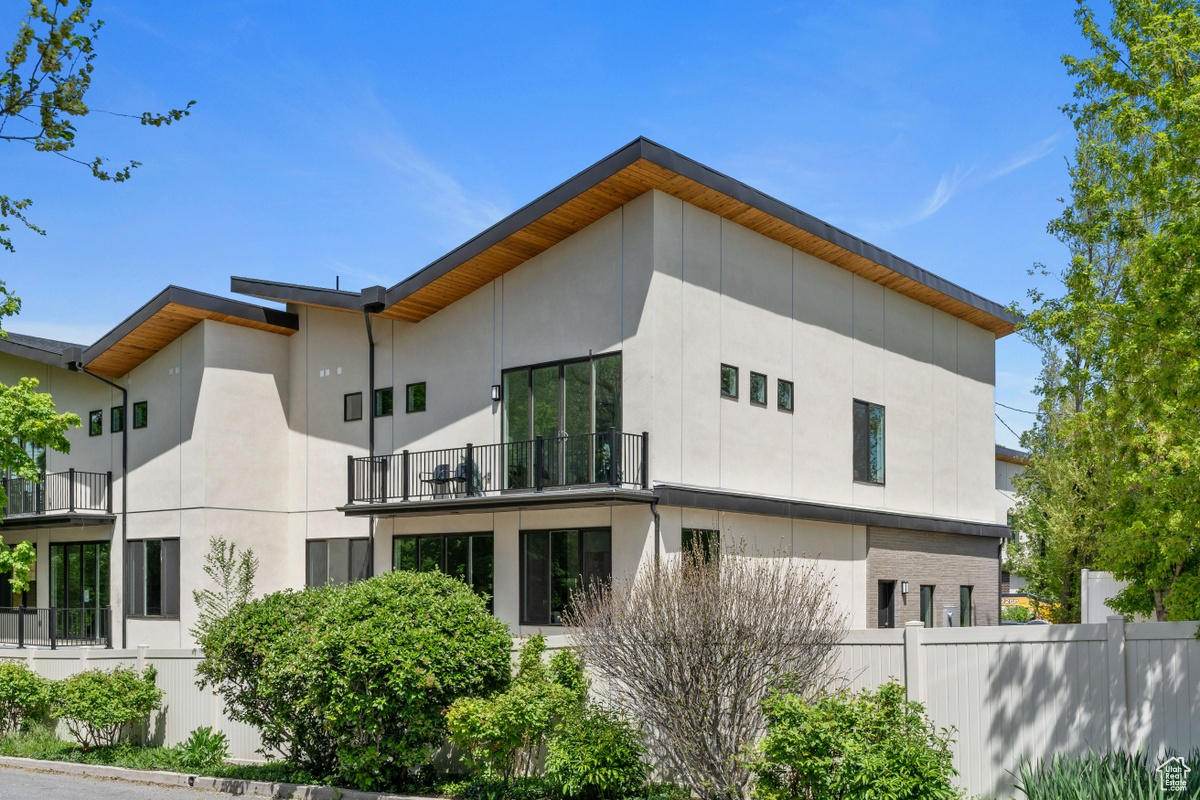 Exterior space featuring a balcony, fence, and stucco siding