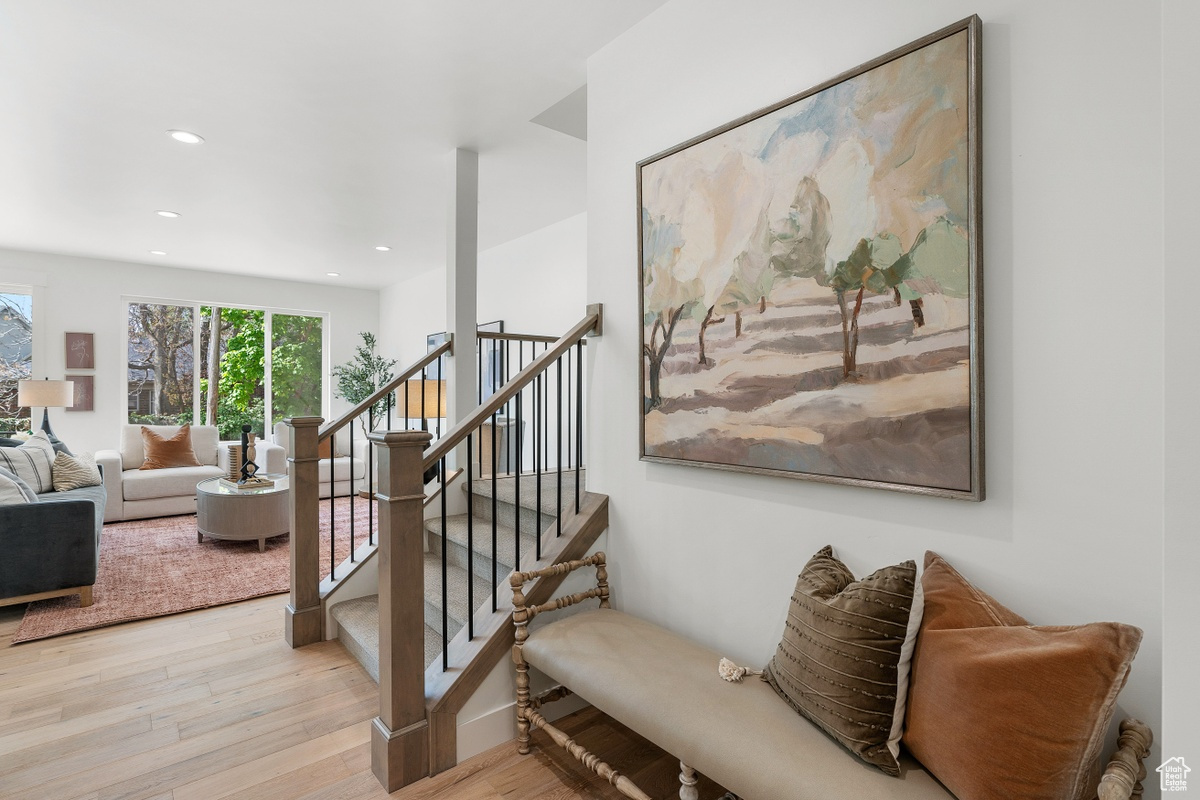 Staircase with wood finished floors and recessed lighting