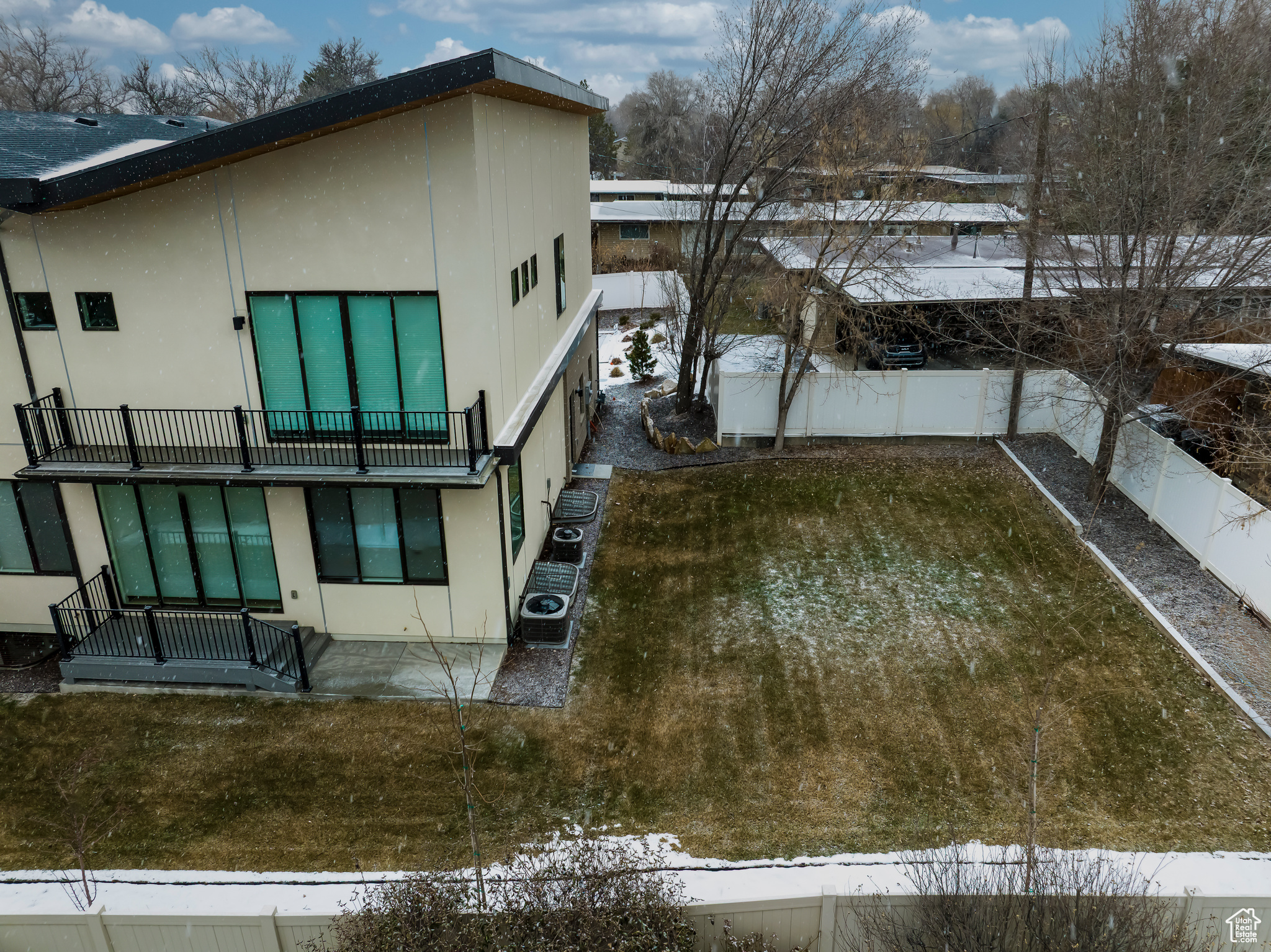 Snow covered property with central AC, fence, and stucco siding