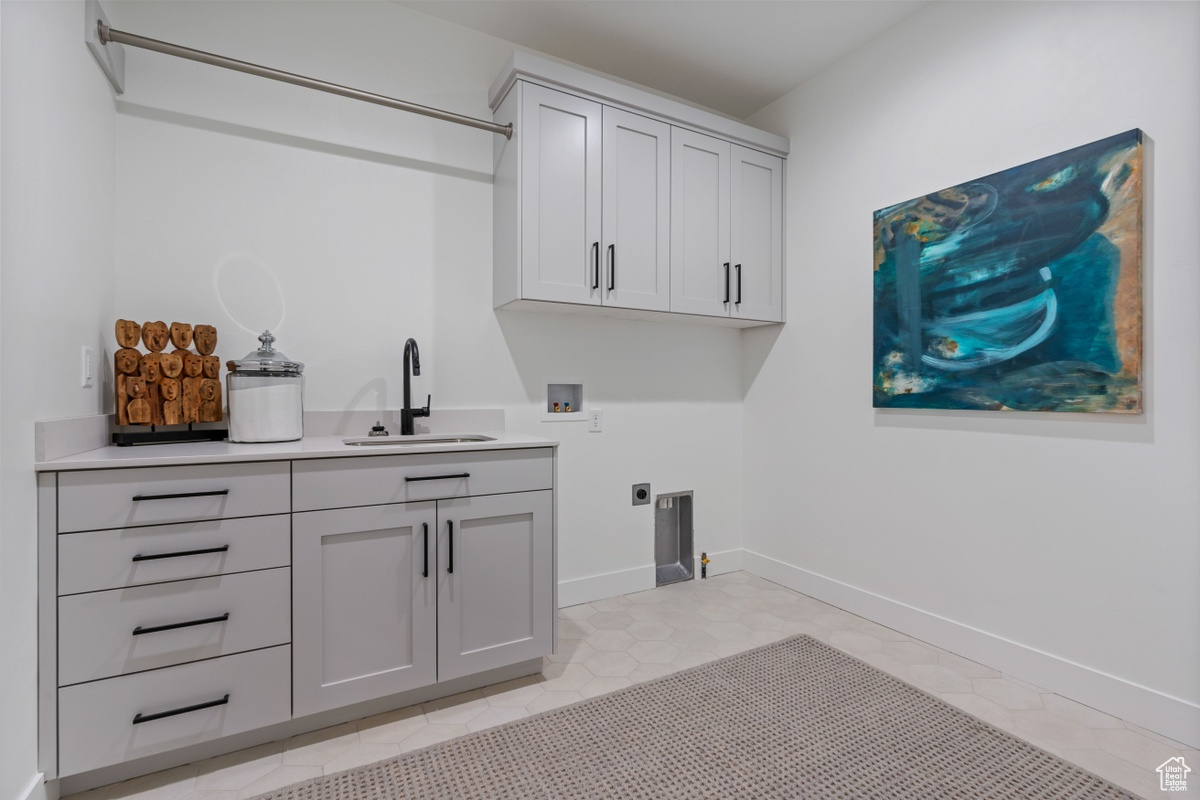 Washroom featuring cabinet space, baseboards, hookup for an electric dryer, washer hookup, and a sink