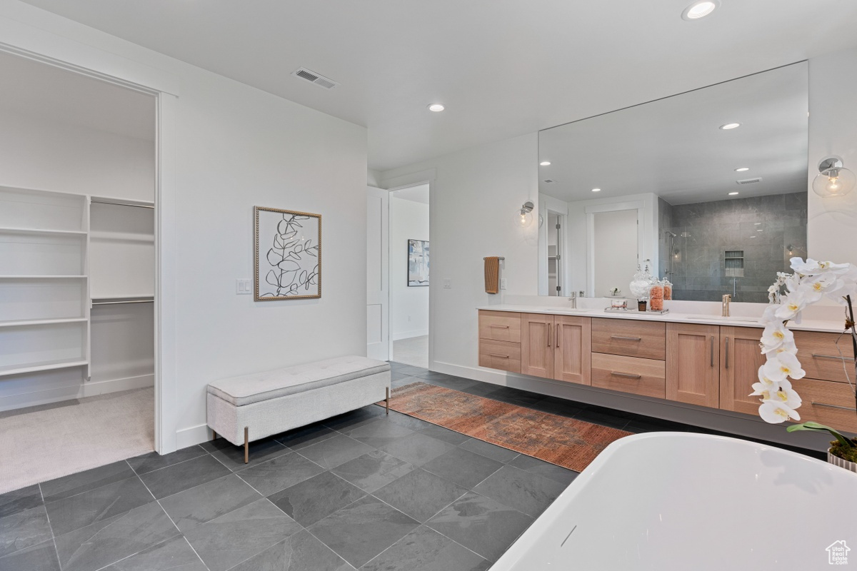 Full bathroom featuring recessed lighting, a sink, a spacious closet, a tile shower, and double vanity