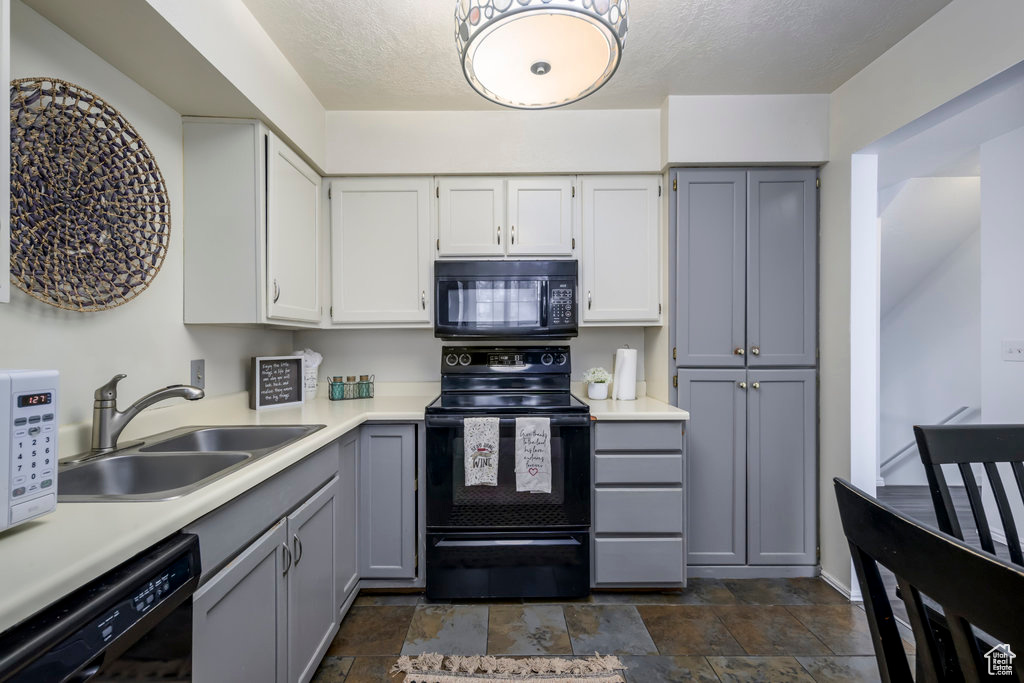 Kitchen featuring black appliances, a sink, light countertops, and gray cabinetry