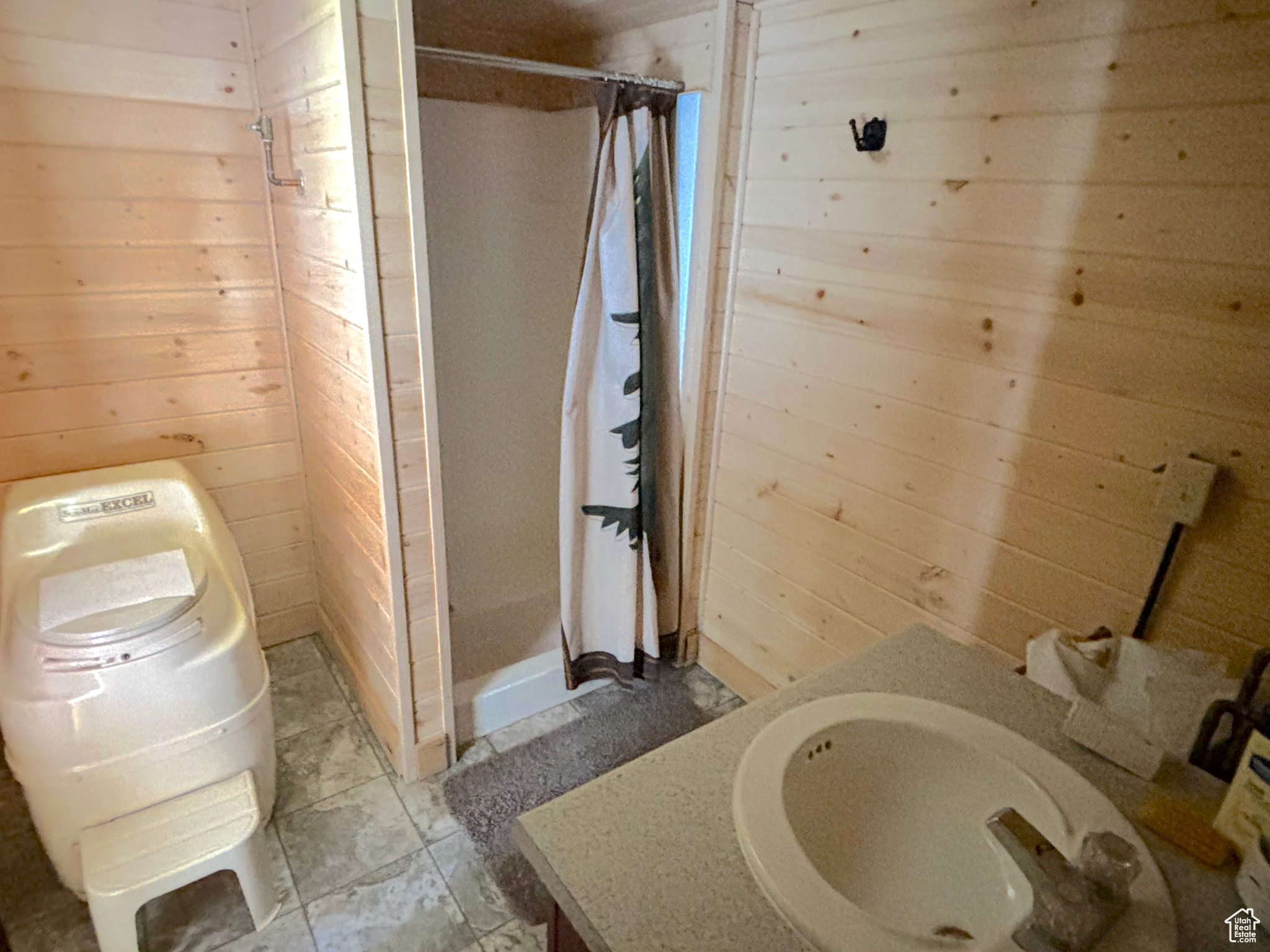 Full bathroom featuring wood walls, a stall shower, and vanity