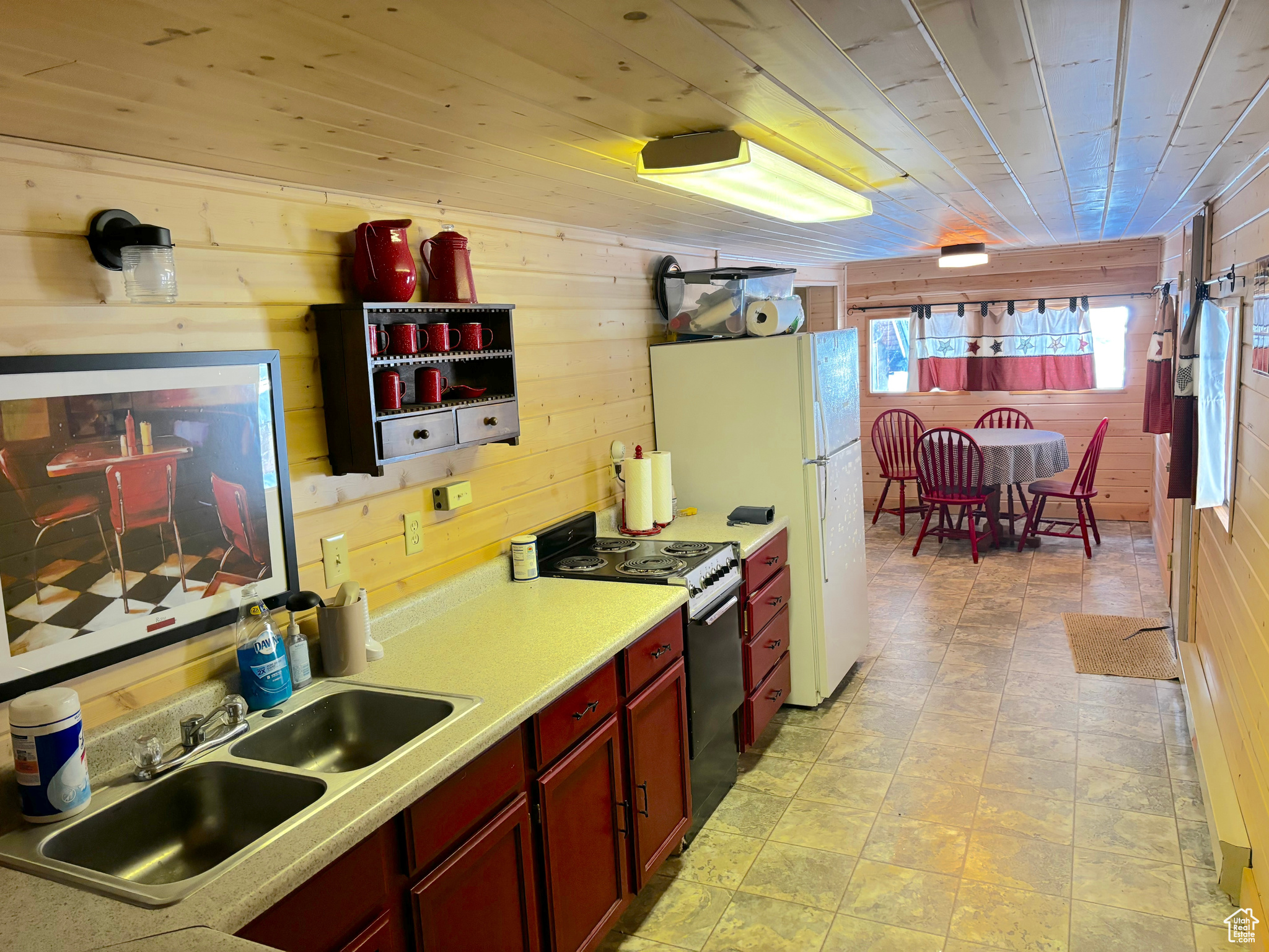 Kitchen featuring electric stove, light countertops, a sink, and wood walls