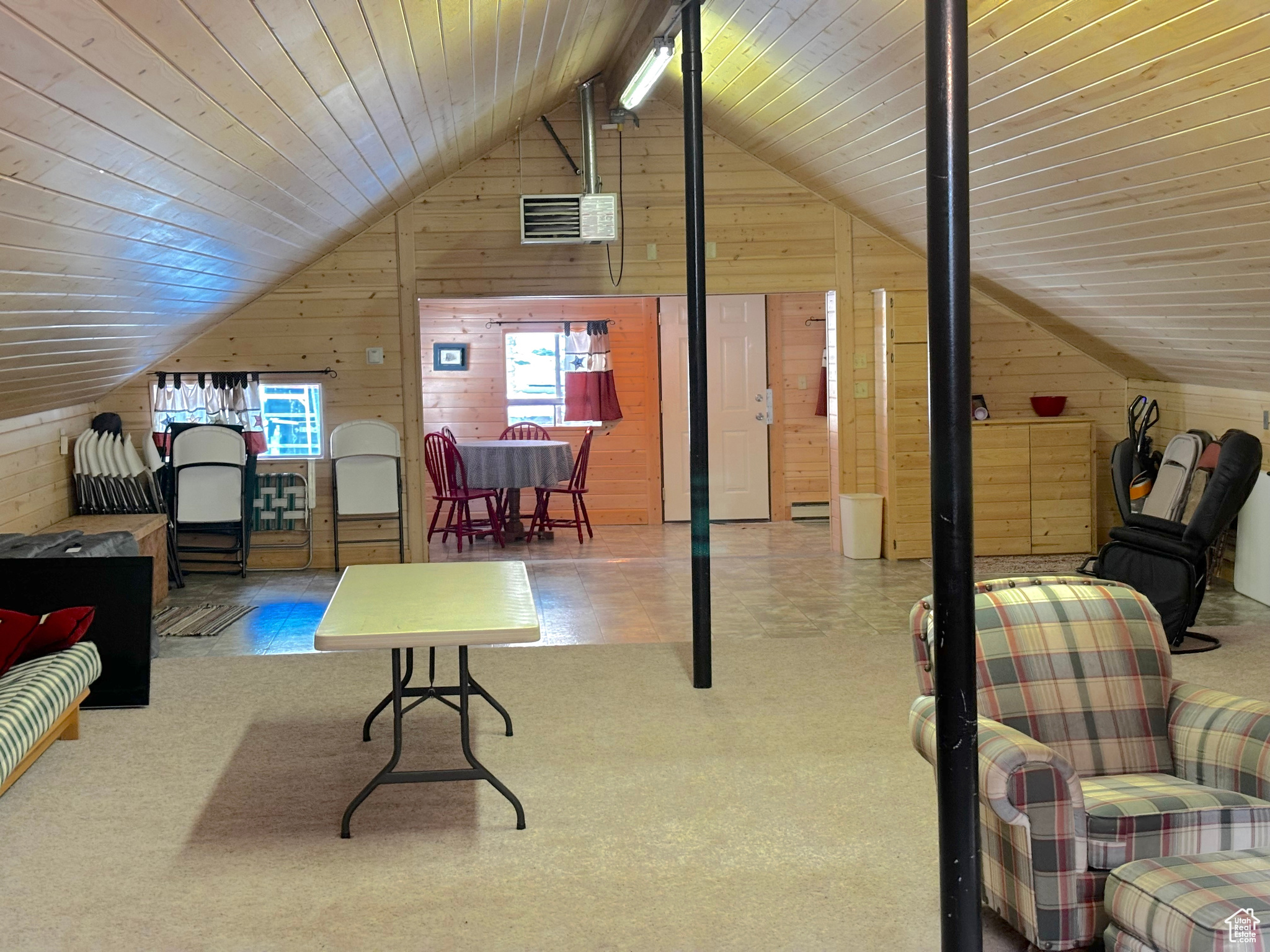 Interior space featuring lofted ceiling, wood ceiling, visible vents, and wooden walls