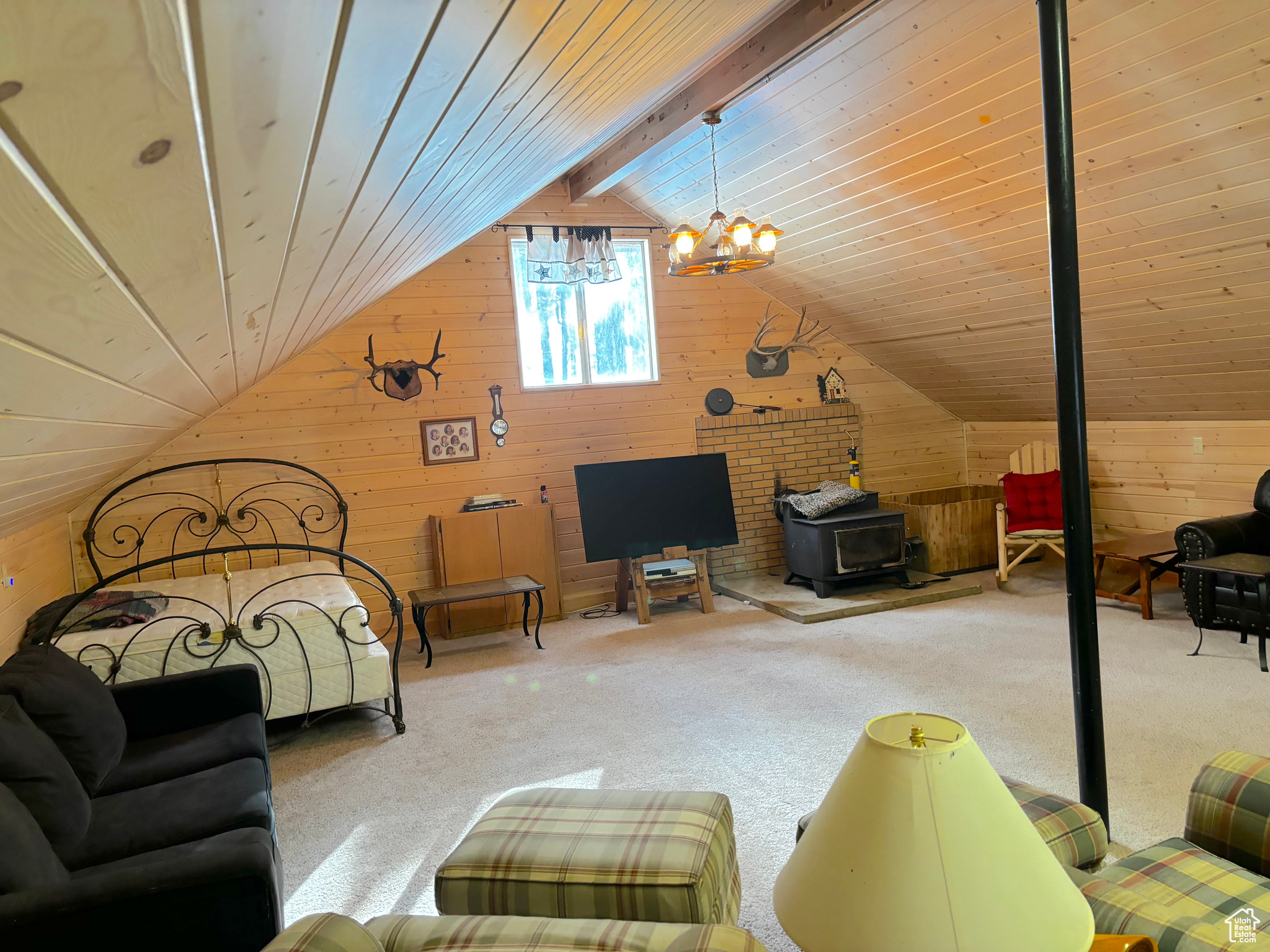 Bedroom with lofted ceiling with beams, light carpet, wood walls, wood ceiling, and an inviting chandelier