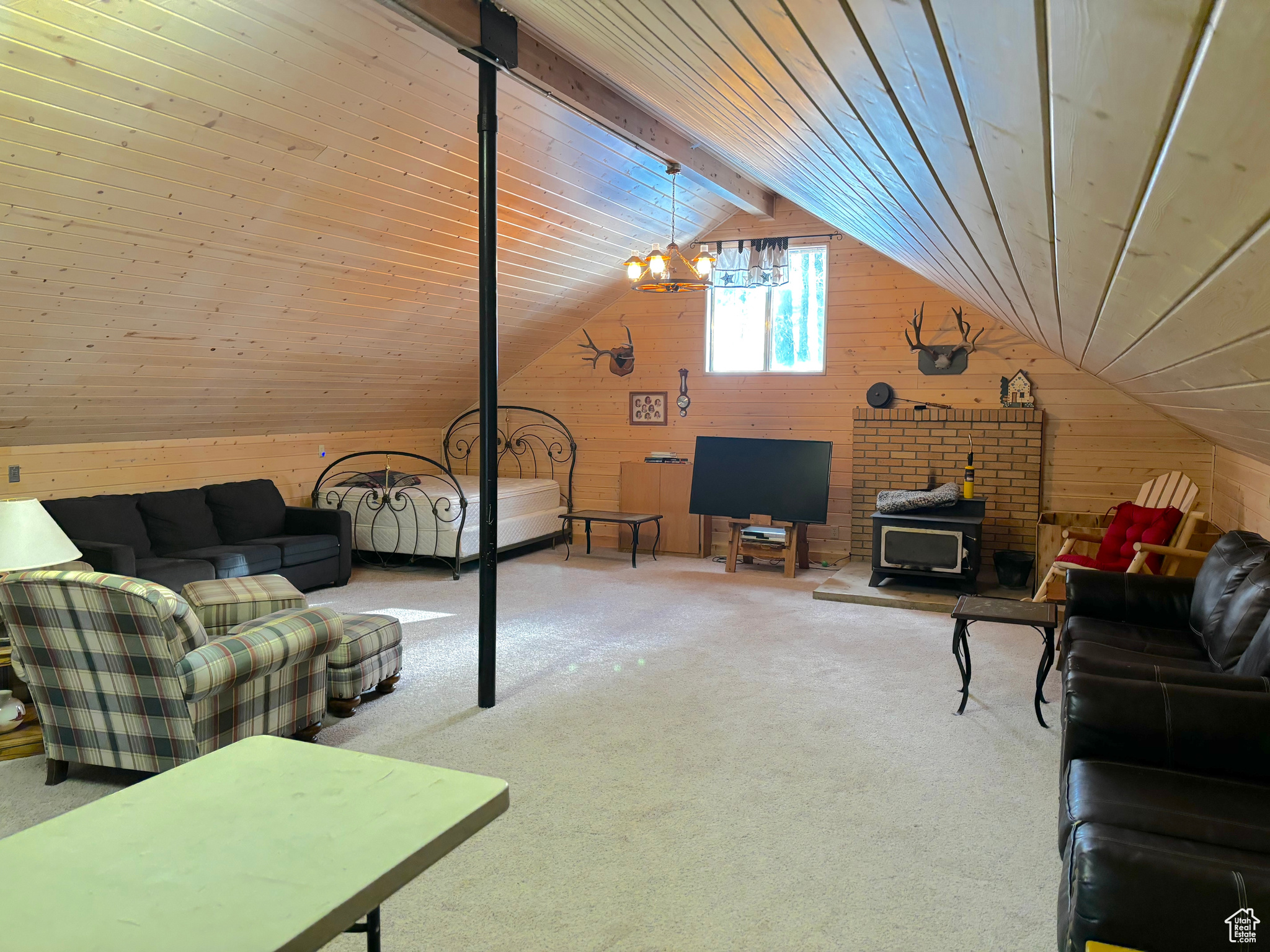 Living room featuring lofted ceiling, wooden ceiling, carpet floors, wood walls, and a wood stove