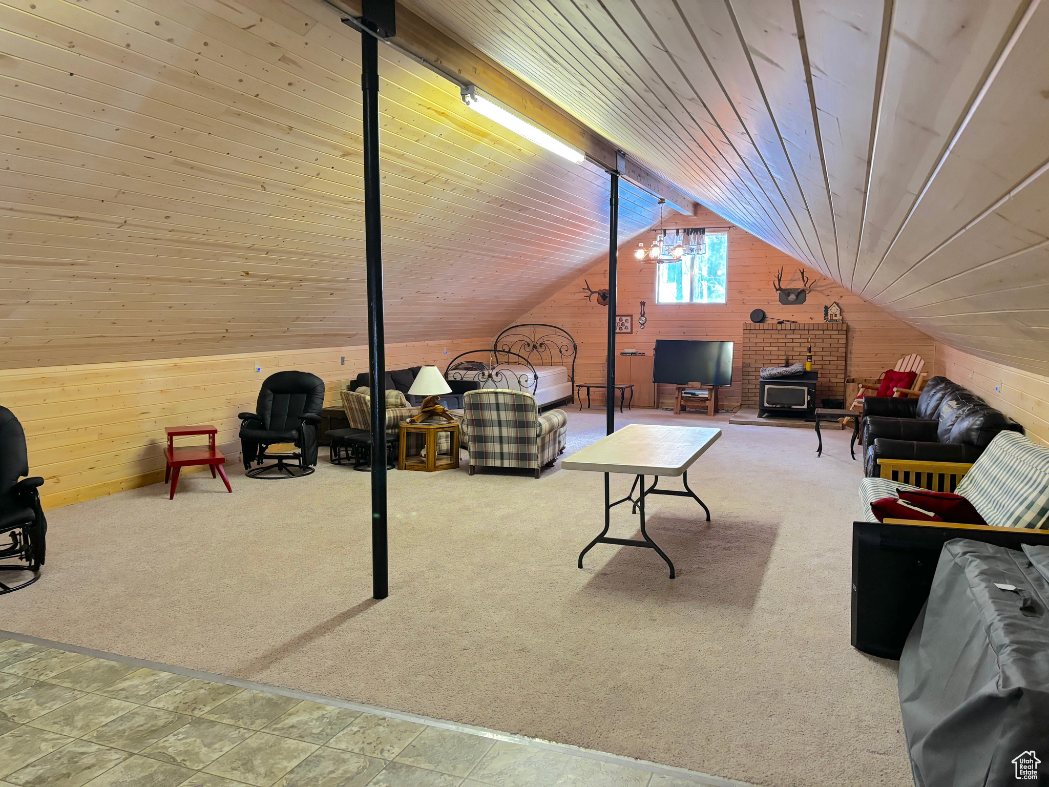 Interior space featuring lofted ceiling, wooden ceiling, a wood stove, carpet flooring, and wood walls