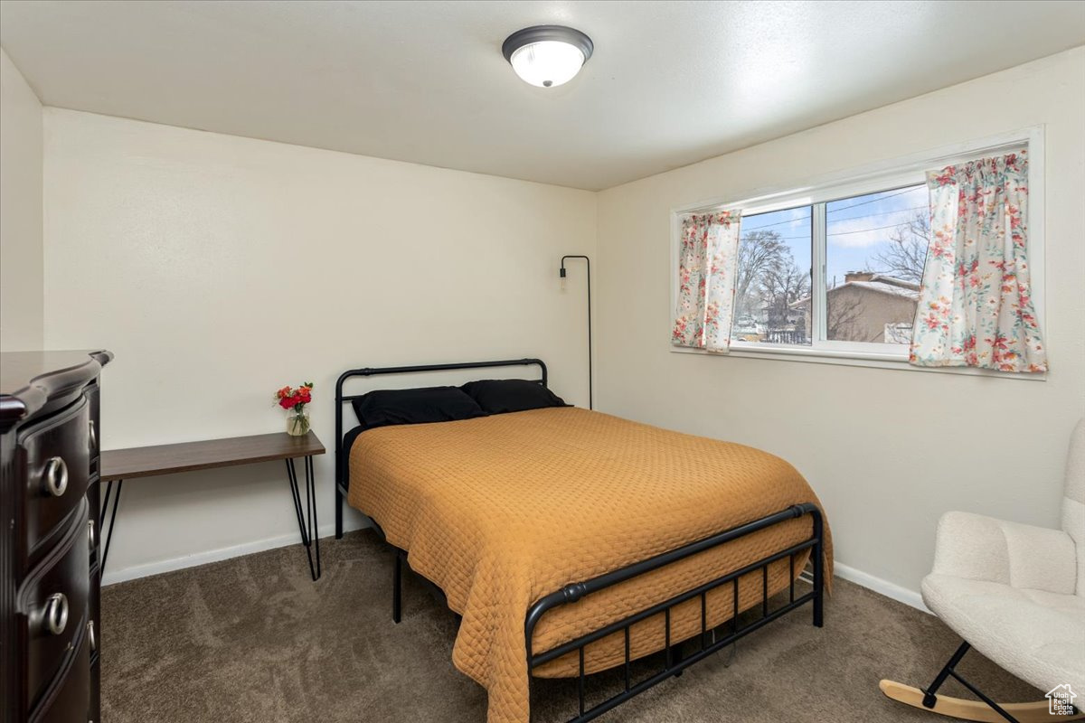 Bedroom featuring dark carpet and baseboards