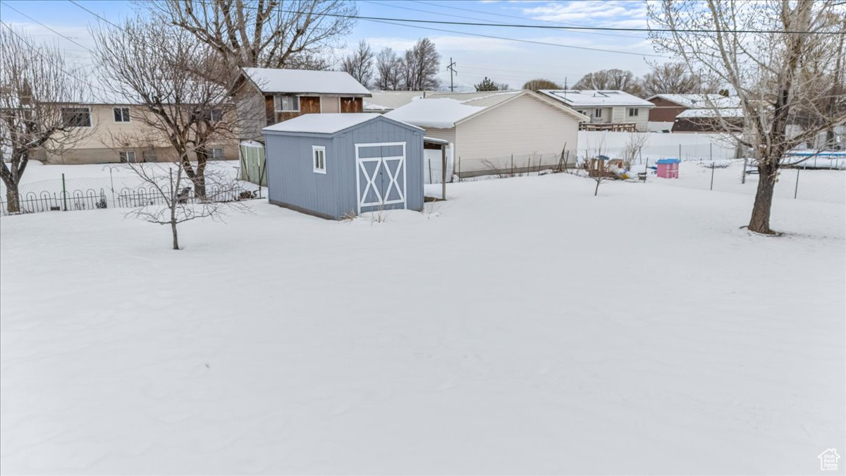 View of front facade with an outbuilding, a storage unit, and fence