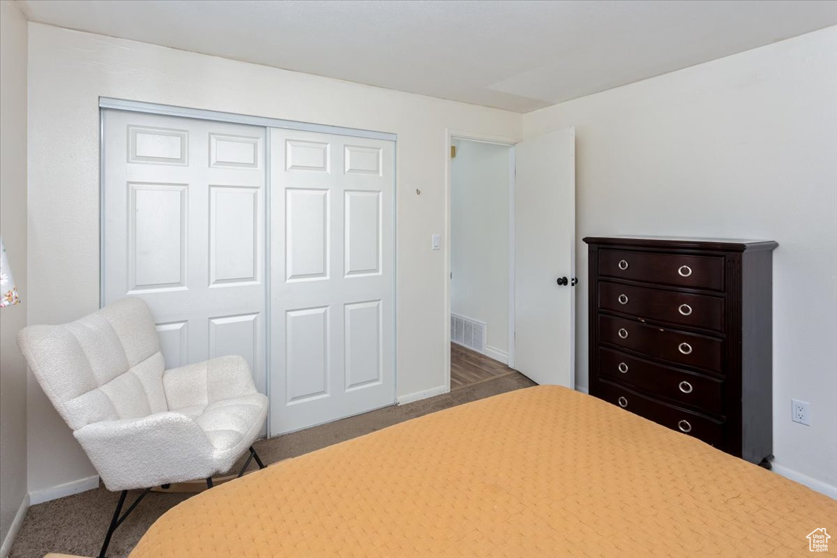 Carpeted bedroom with baseboards, visible vents, and a closet