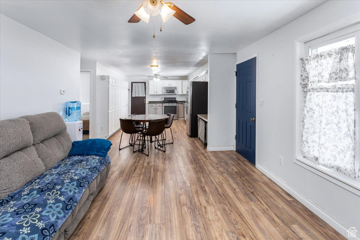 Living area featuring a ceiling fan, a wealth of natural light, baseboards, and wood finished floors