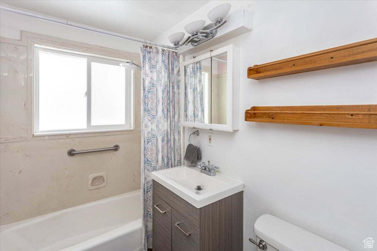 Bathroom with shower / bath combination with curtain, vanity, and toilet