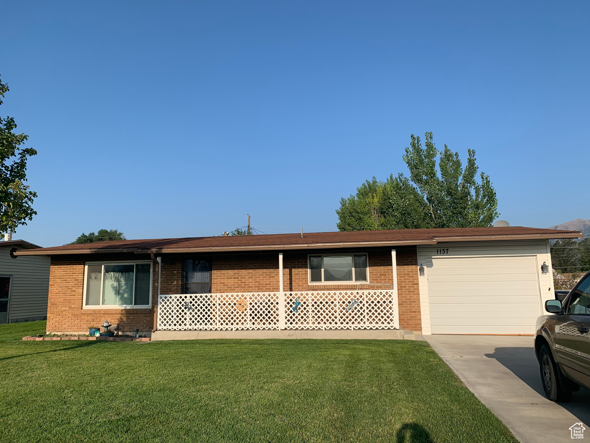 Ranch-style home featuring a front lawn, an attached garage, brick siding, and concrete driveway