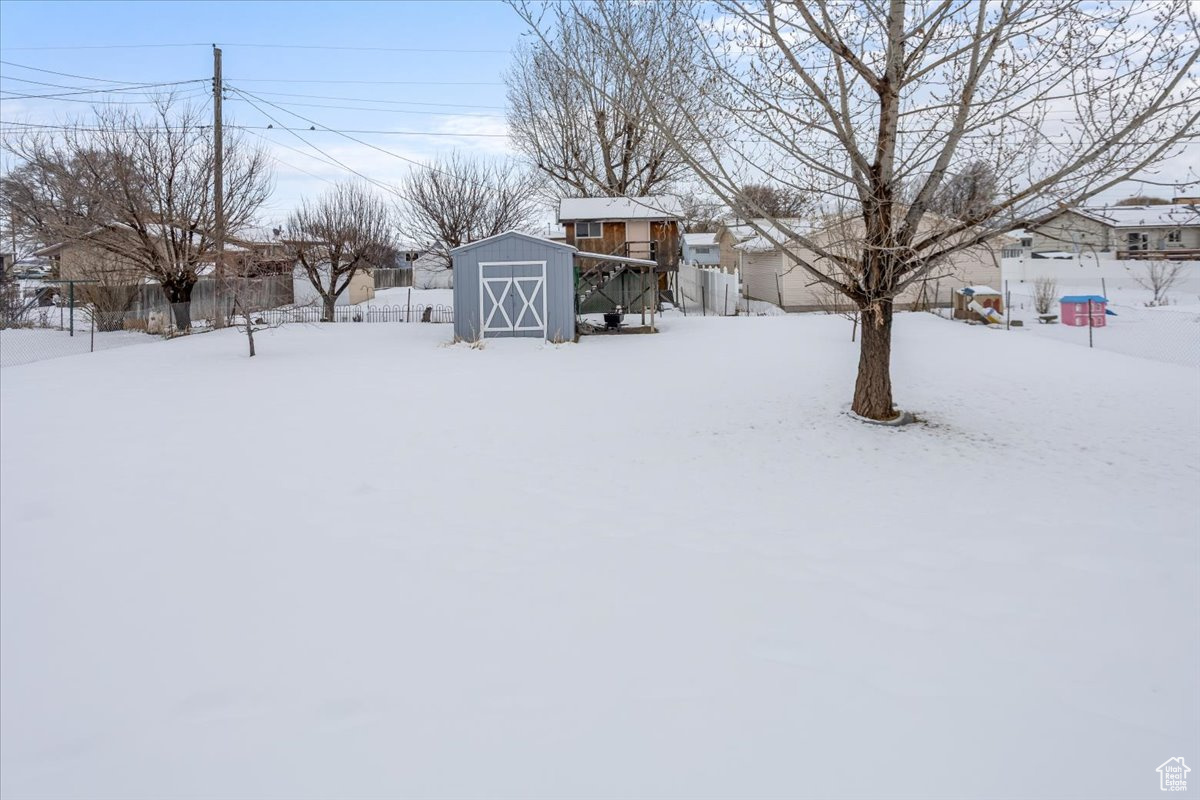 Yard covered in snow featuring an outdoor structure and a storage unit
