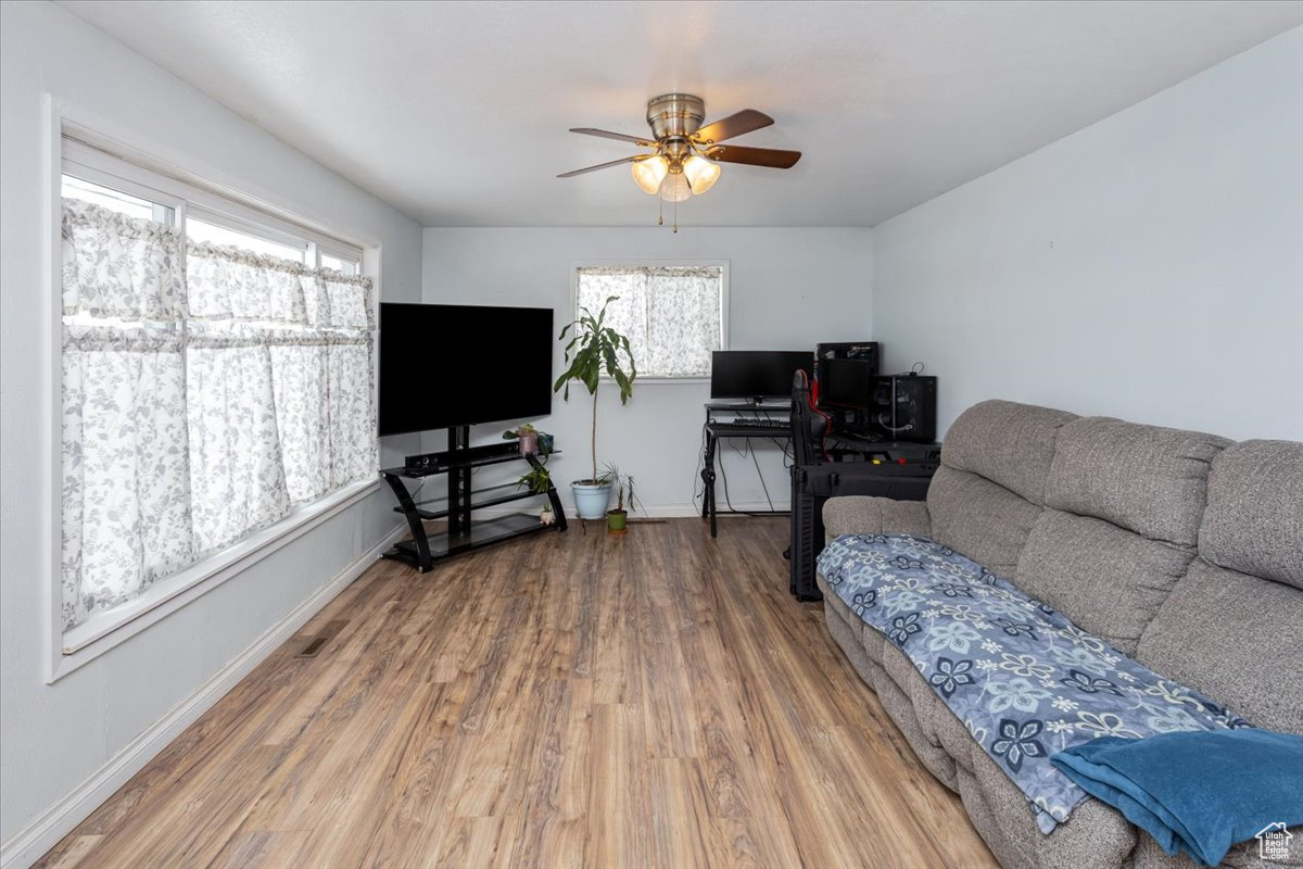 Living room with ceiling fan, baseboards, and wood finished floors