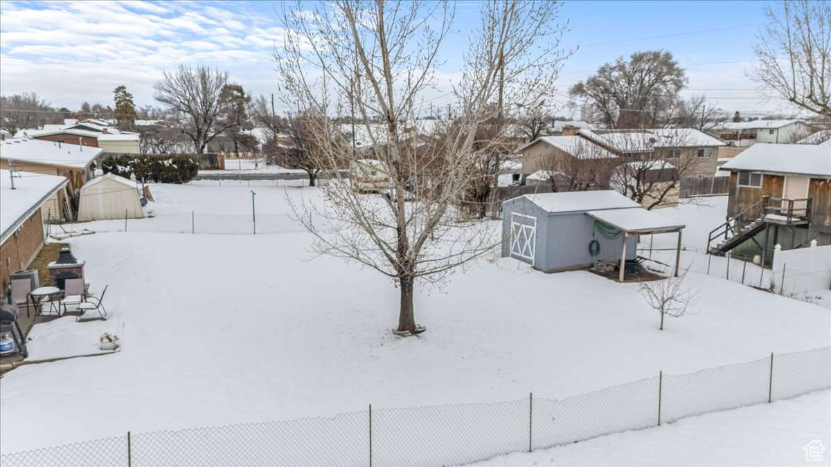 Yard covered in snow featuring fence and an outdoor structure