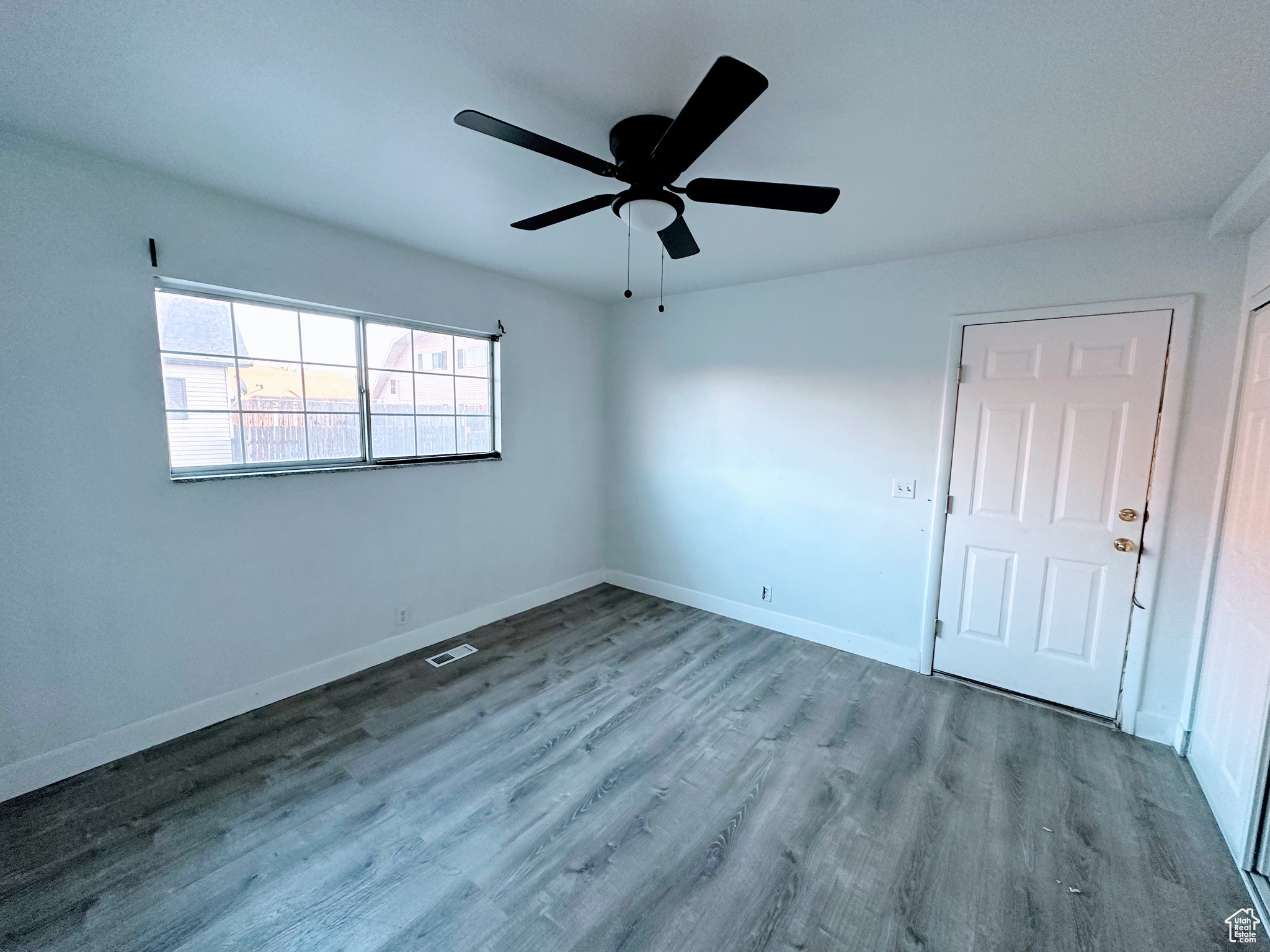 Spare room with a ceiling fan, visible vents, light wood-style flooring, and baseboards