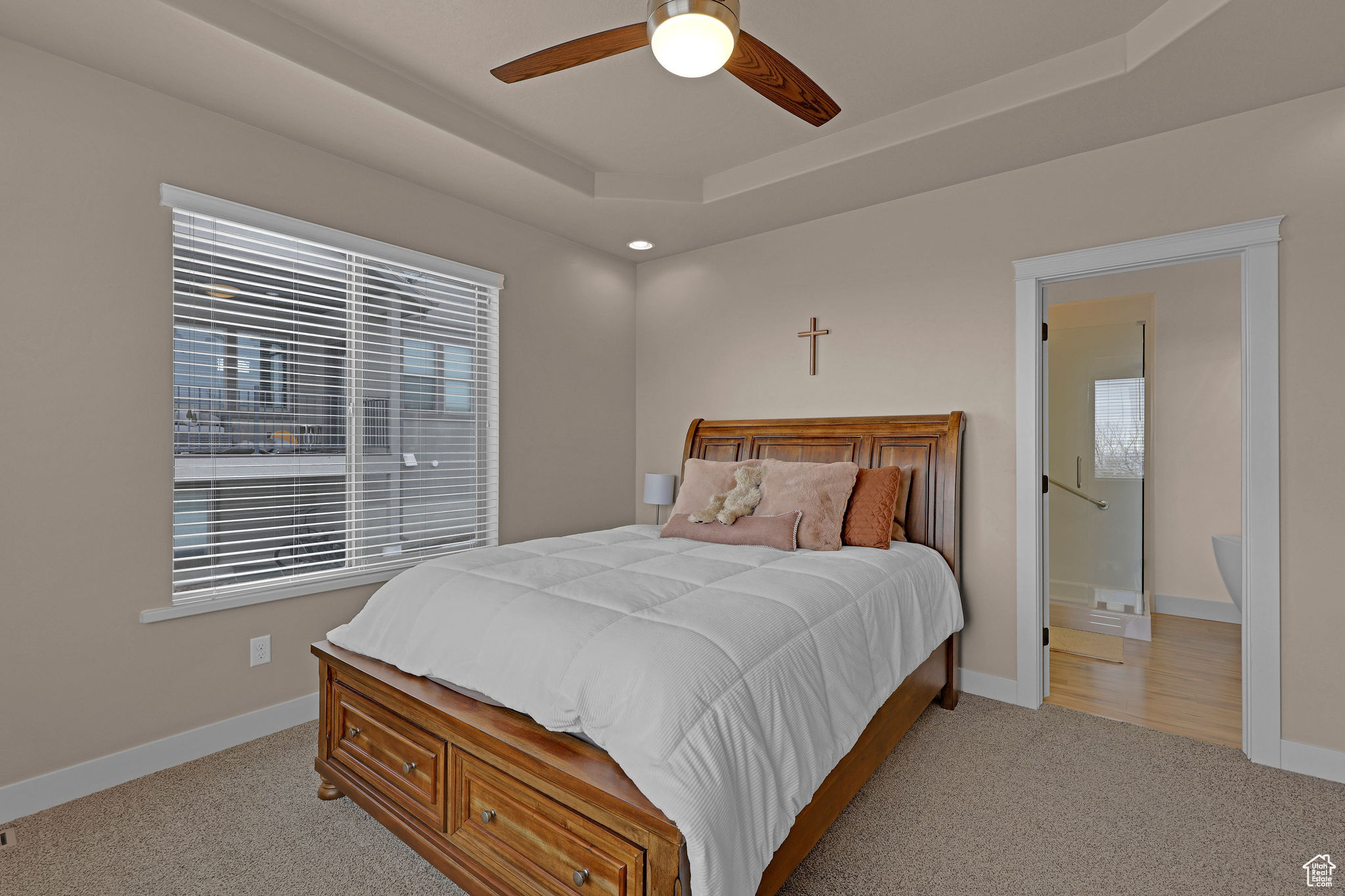 Carpeted bedroom featuring a tray ceiling and ceiling fan