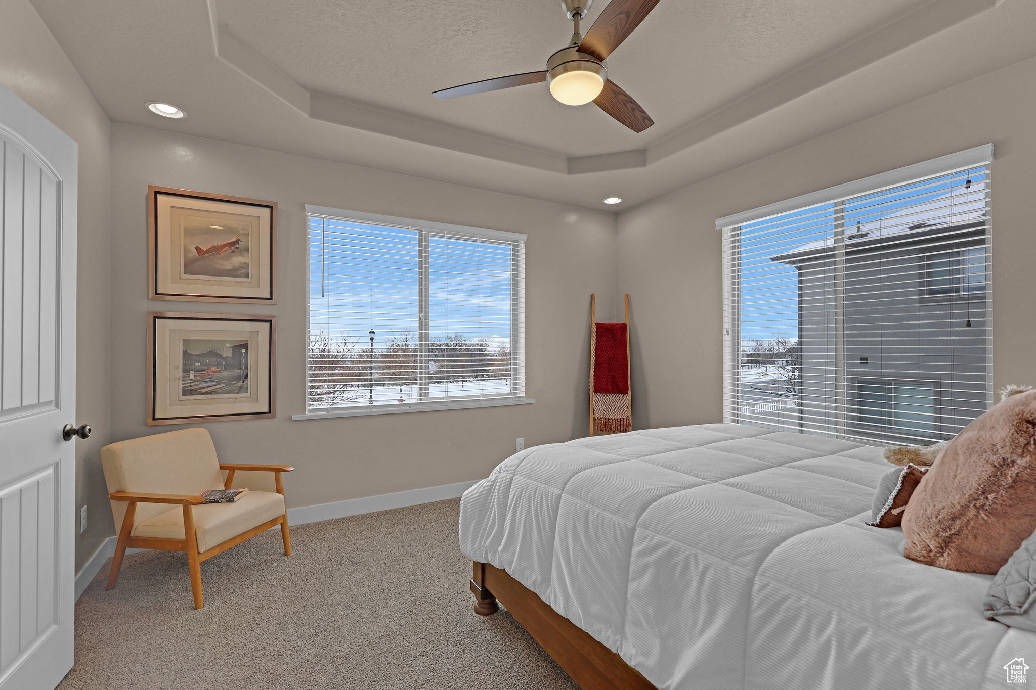 Bedroom featuring a tray ceiling, ceiling fan, and light carpet