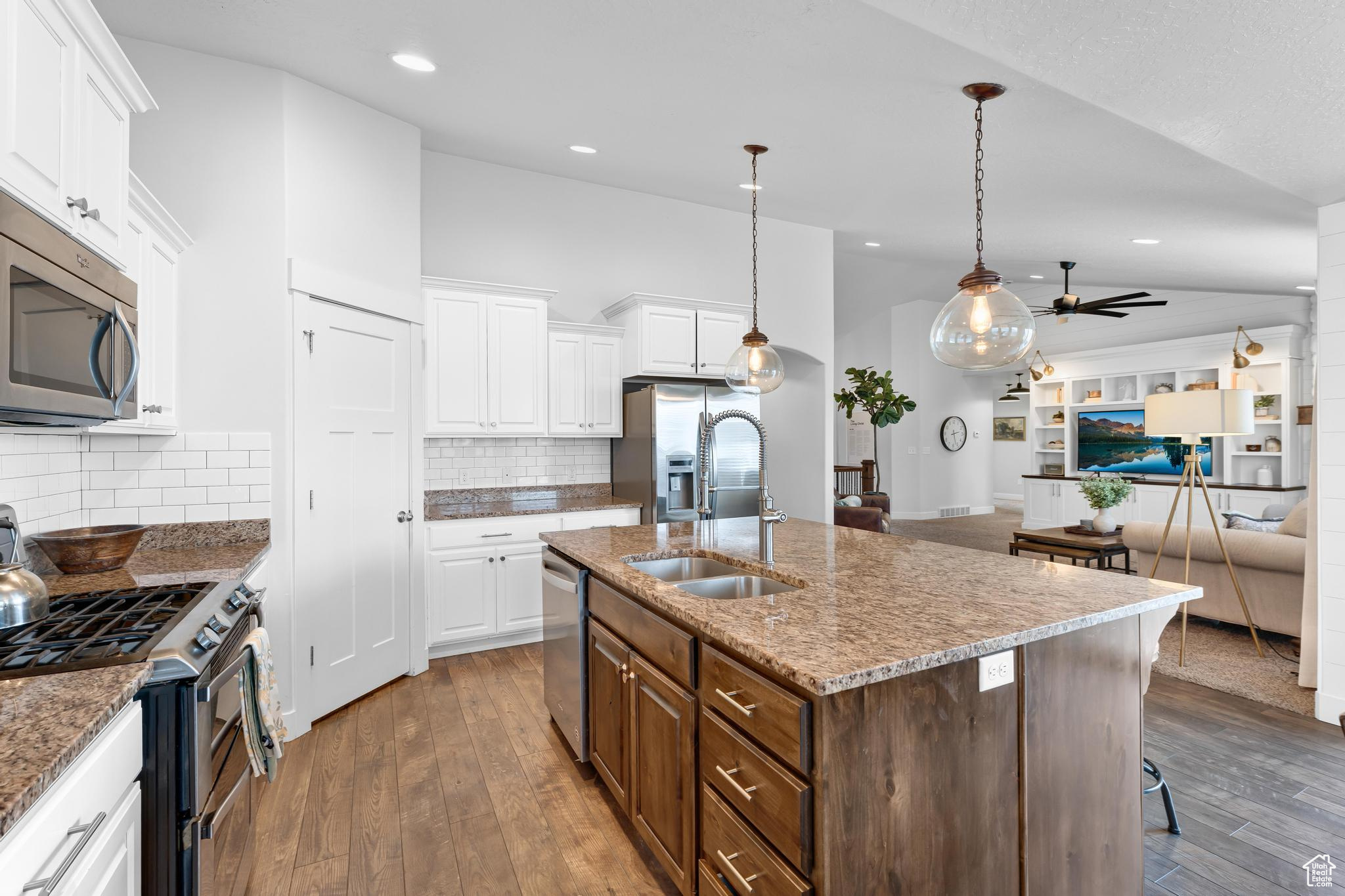 Kitchen with a sink, white cabinetry, open floor plan, appliances with stainless steel finishes, and an island with sink