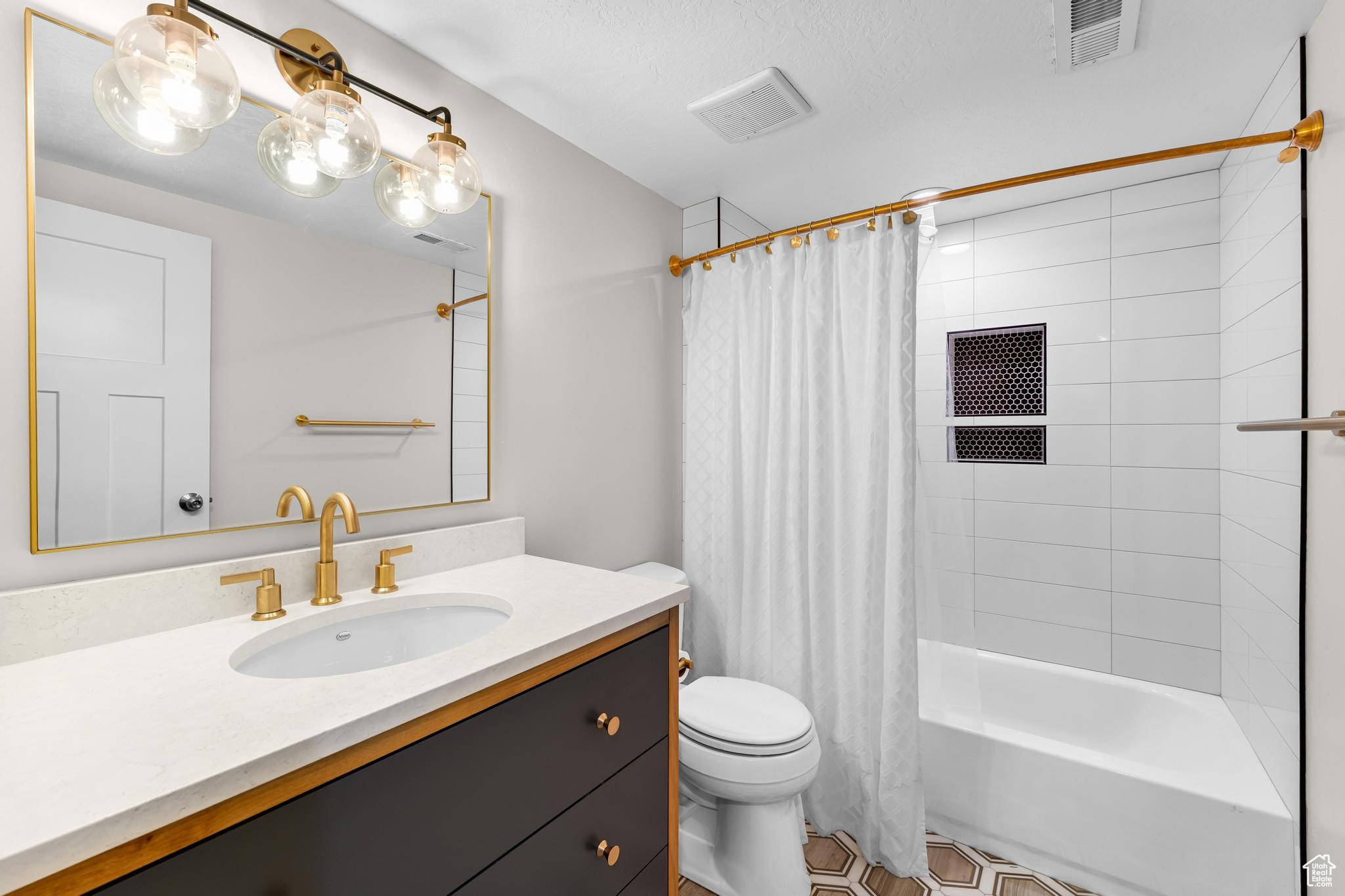 Bathroom featuring shower / bath combo, visible vents, vanity, and toilet