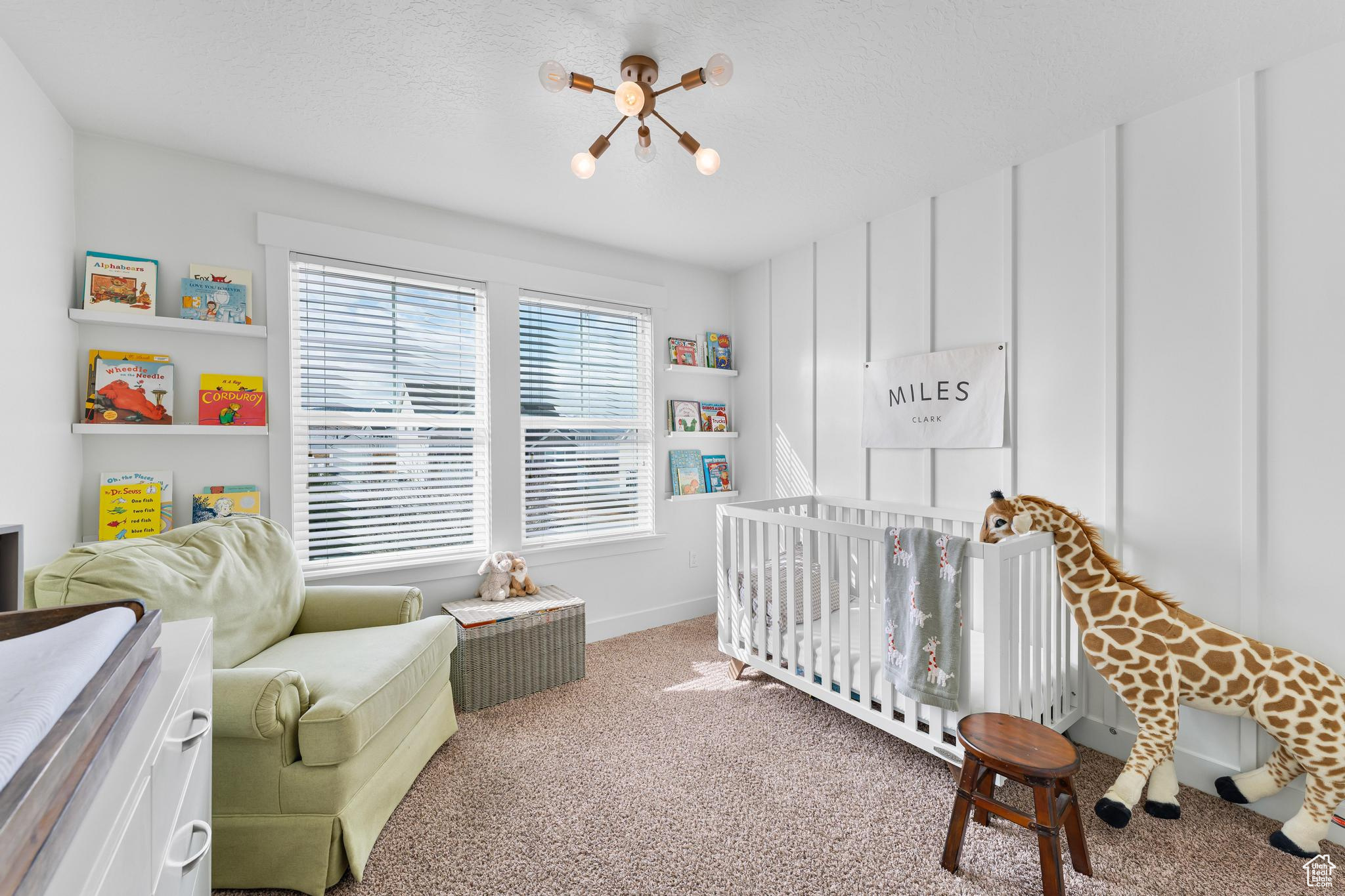 Bedroom featuring a nursery area, light colored carpet, a textured ceiling, and baseboards
