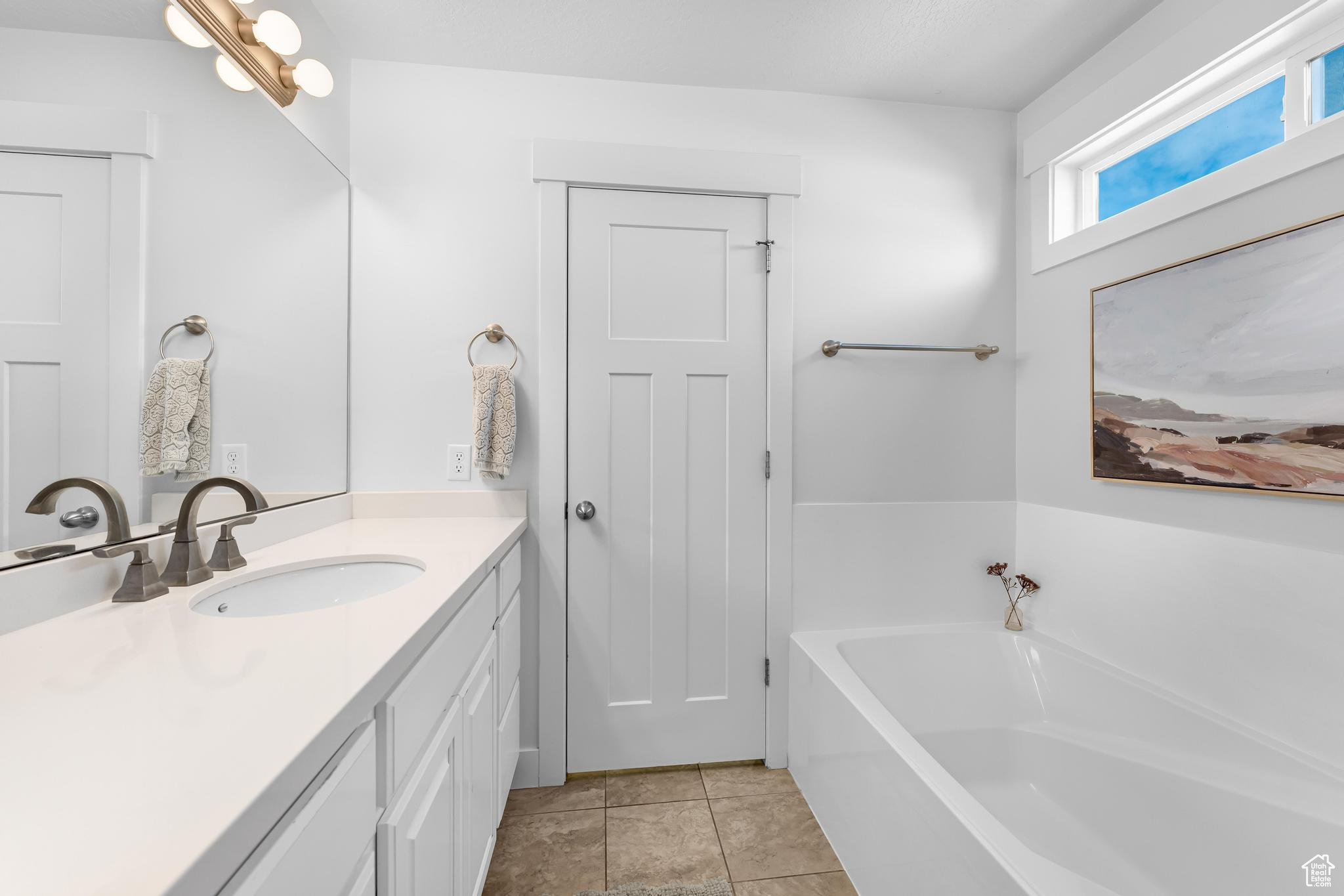 Bathroom with tile patterned flooring, a garden tub, and vanity