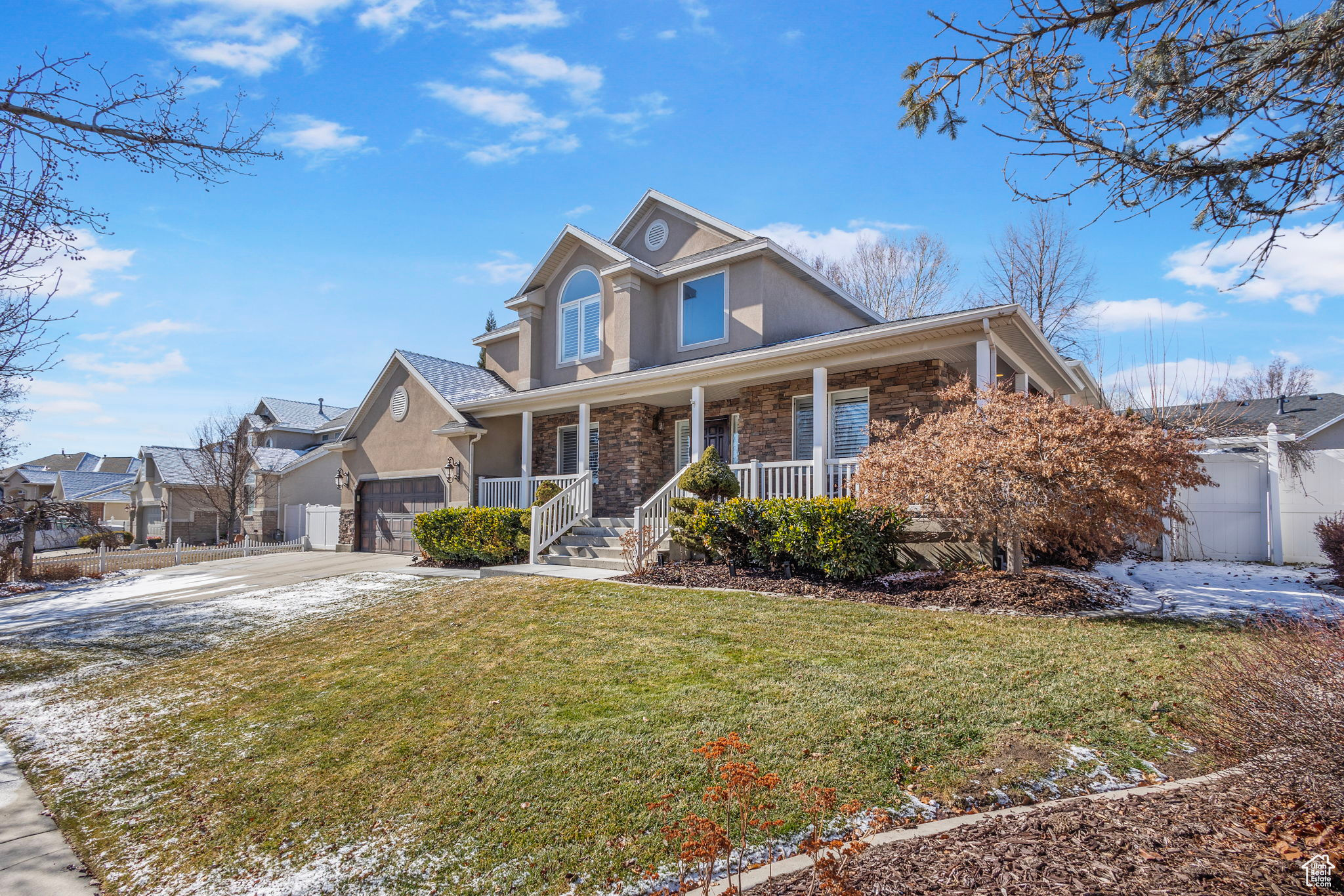 View of property with a garage, a front lawn, and a porch