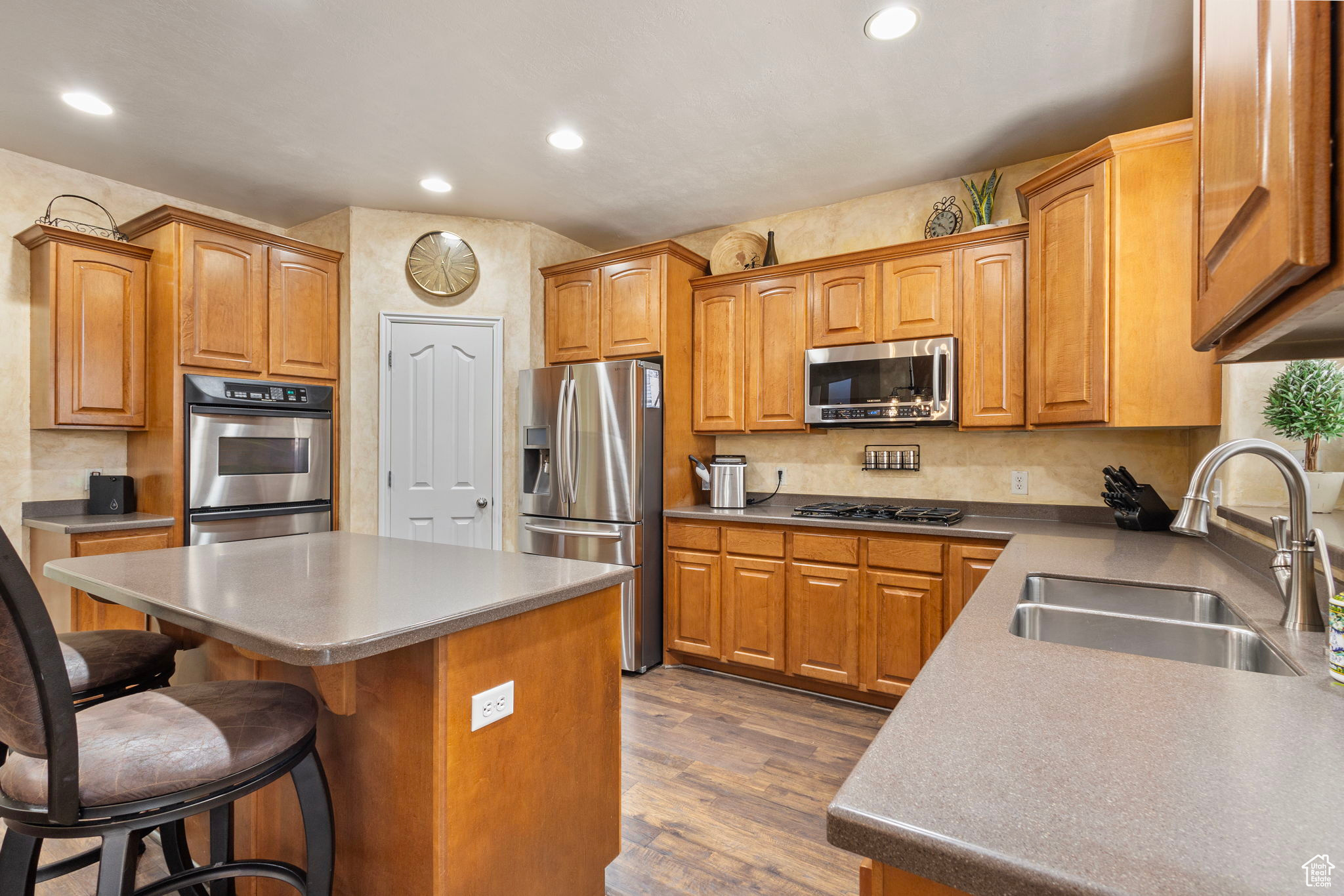 Kitchen with a center island, a breakfast bar, sink, dark wood-type flooring, and appliances with stainless steel finishes