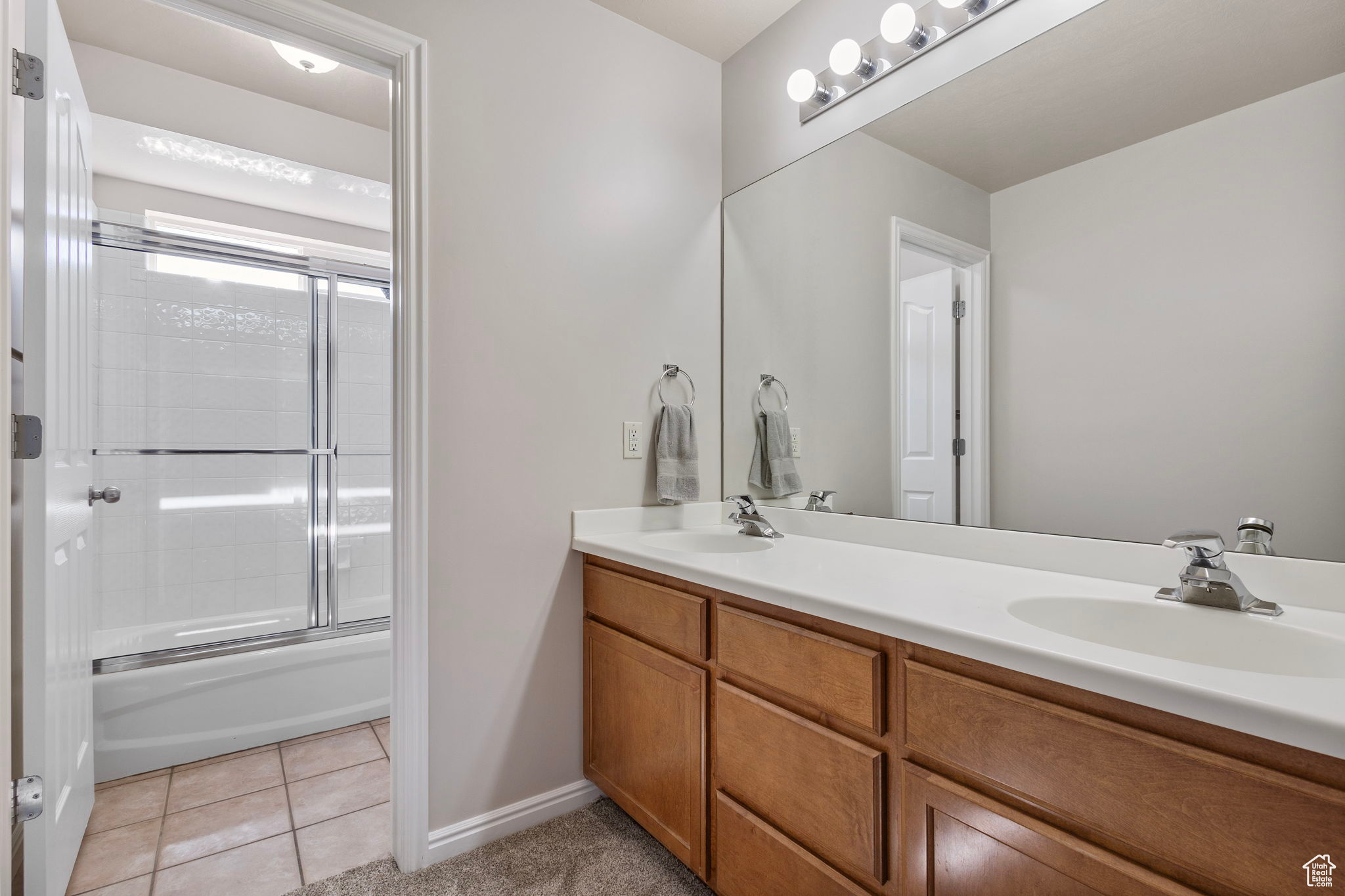 Bathroom featuring tile patterned floors, vanity, and enclosed tub / shower combo