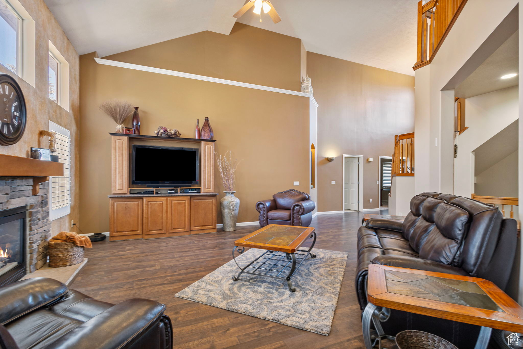 Living room with a fireplace, high vaulted ceiling, dark hardwood / wood-style floors, and ceiling fan