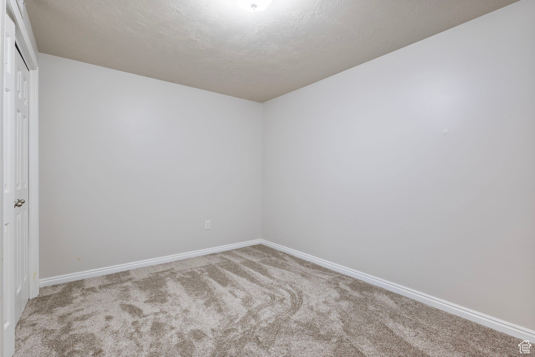 Carpeted empty room featuring a textured ceiling