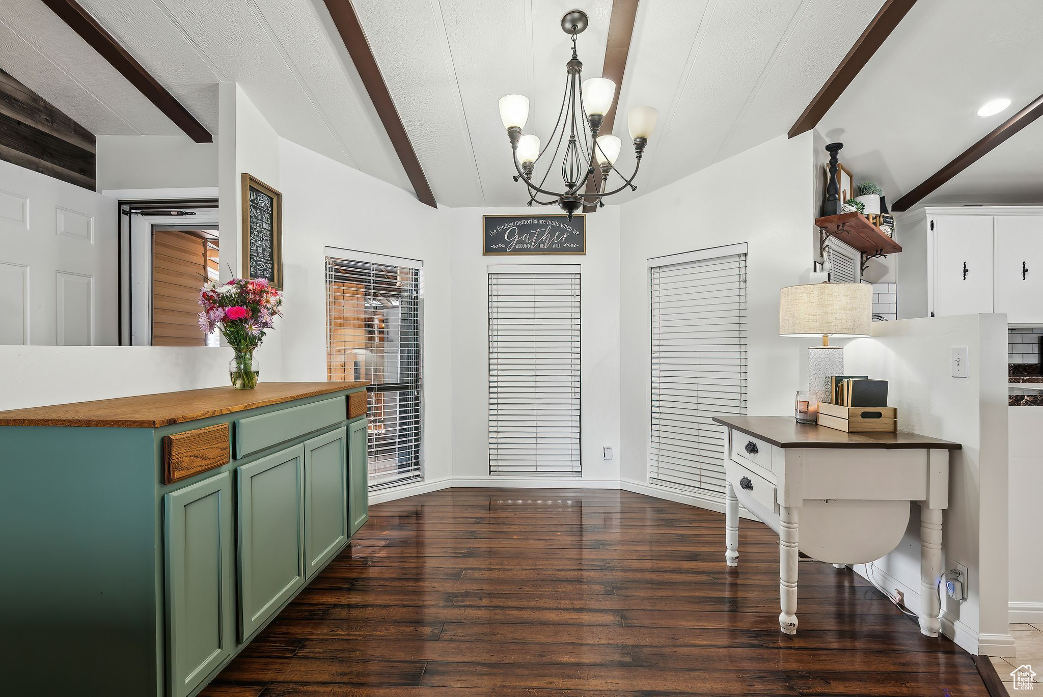 Dining area with lofted ceiling with beams, baseboards, a chandelier, and dark wood-style flooring